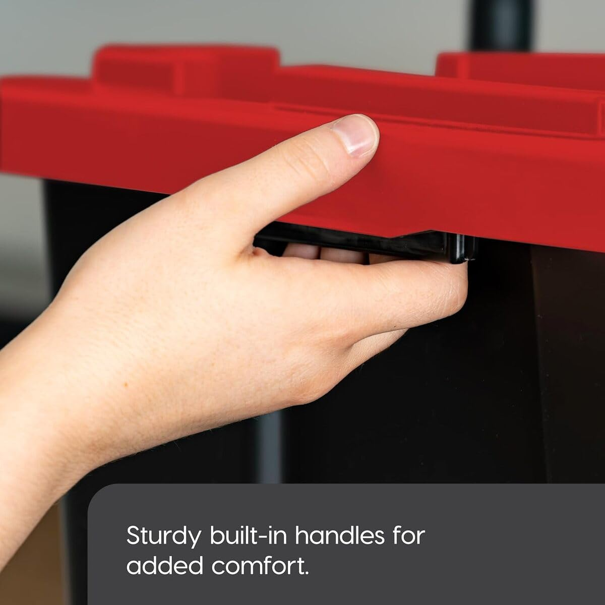 Una mano apre un contenitore nero con coperchio rosso, testo: Robuste maniglie integrate per un maggiore comfort.