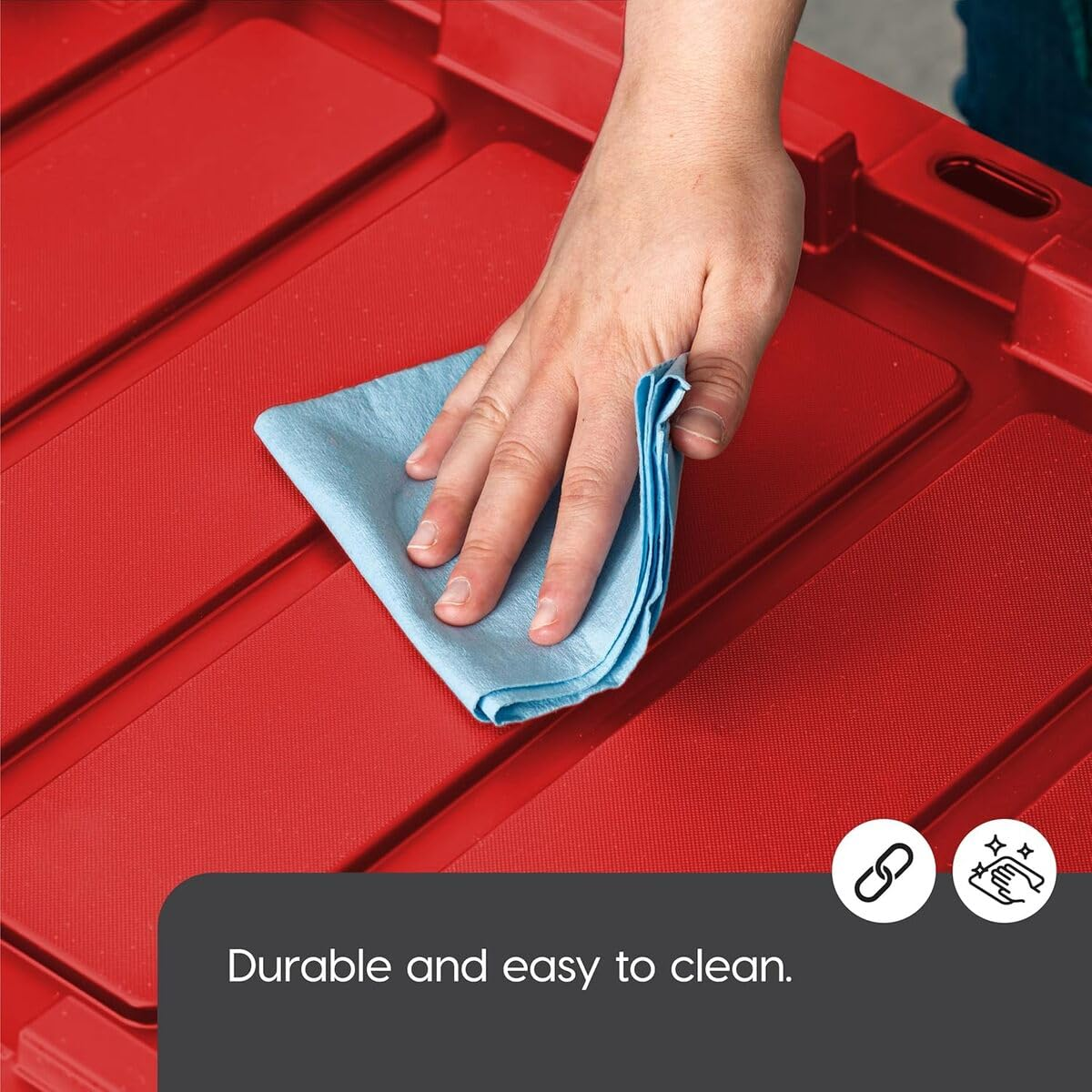 Una mano usa un panno blu per pulire una superficie di plastica rossa.