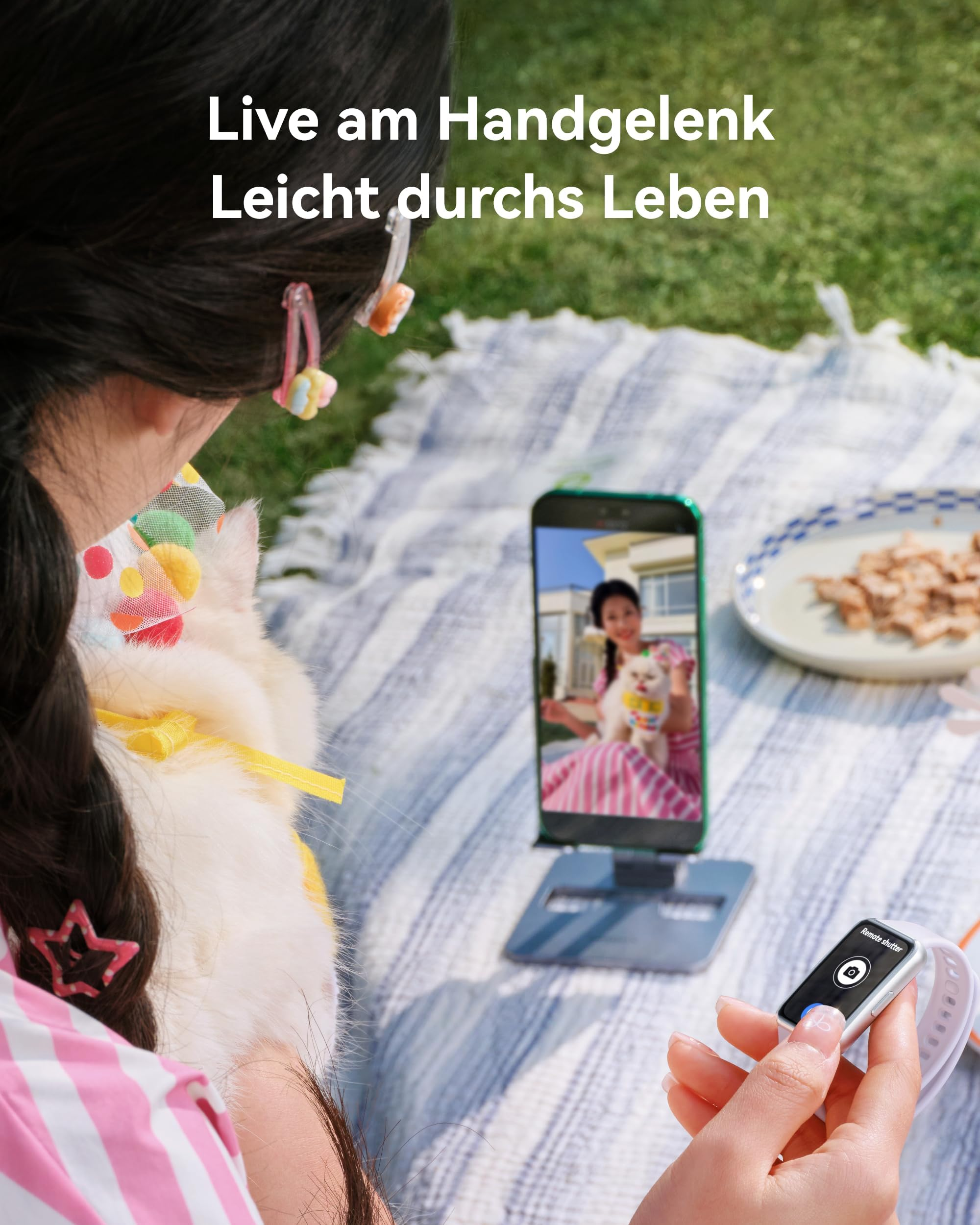 Una donna tiene in mano uno smartwatch mentre guarda il telefono su un supporto che mostra una foto di lei e di un gatto.
