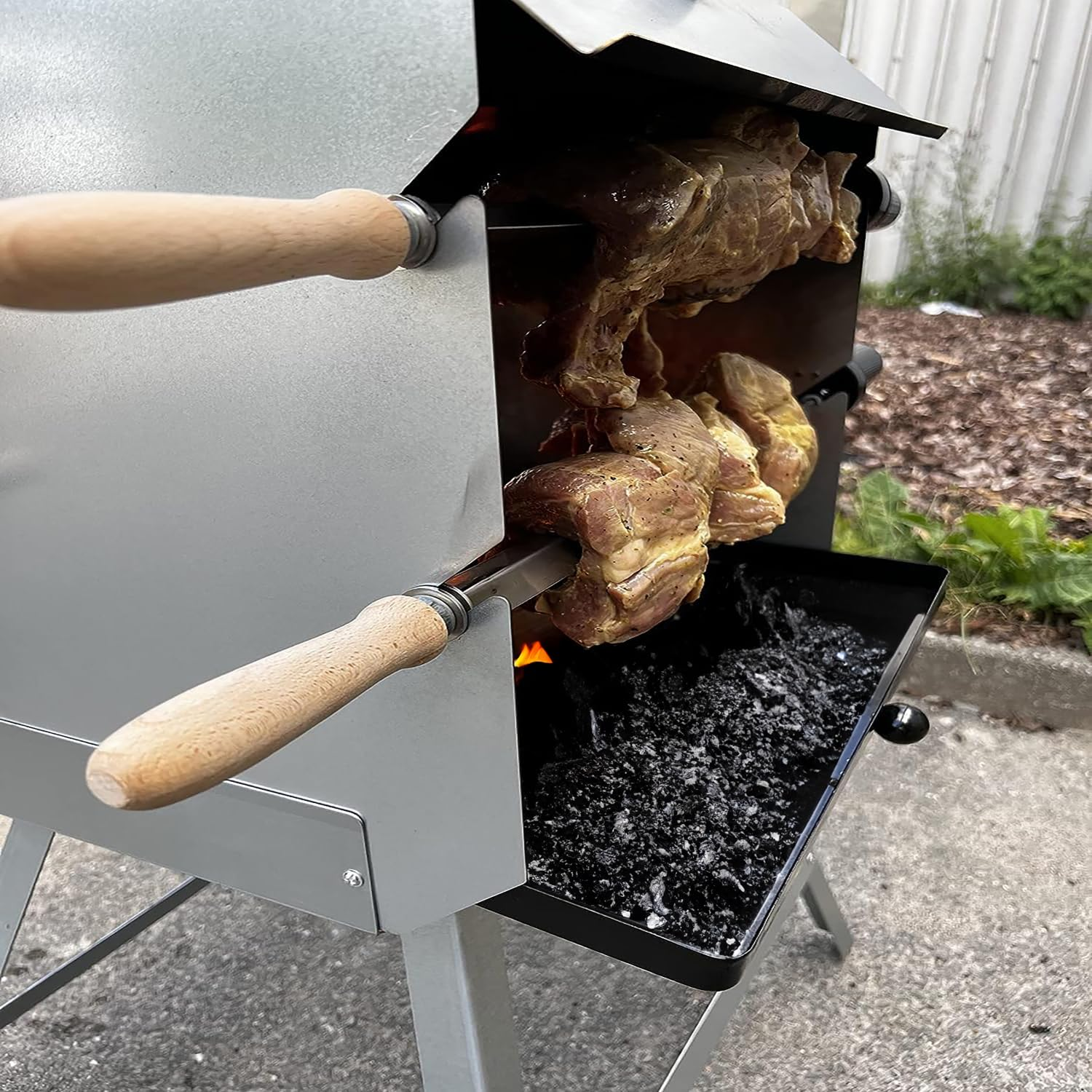 Deux brochettes de viande assaisonnée rôtissant sur du charbon dans un gril métallique.