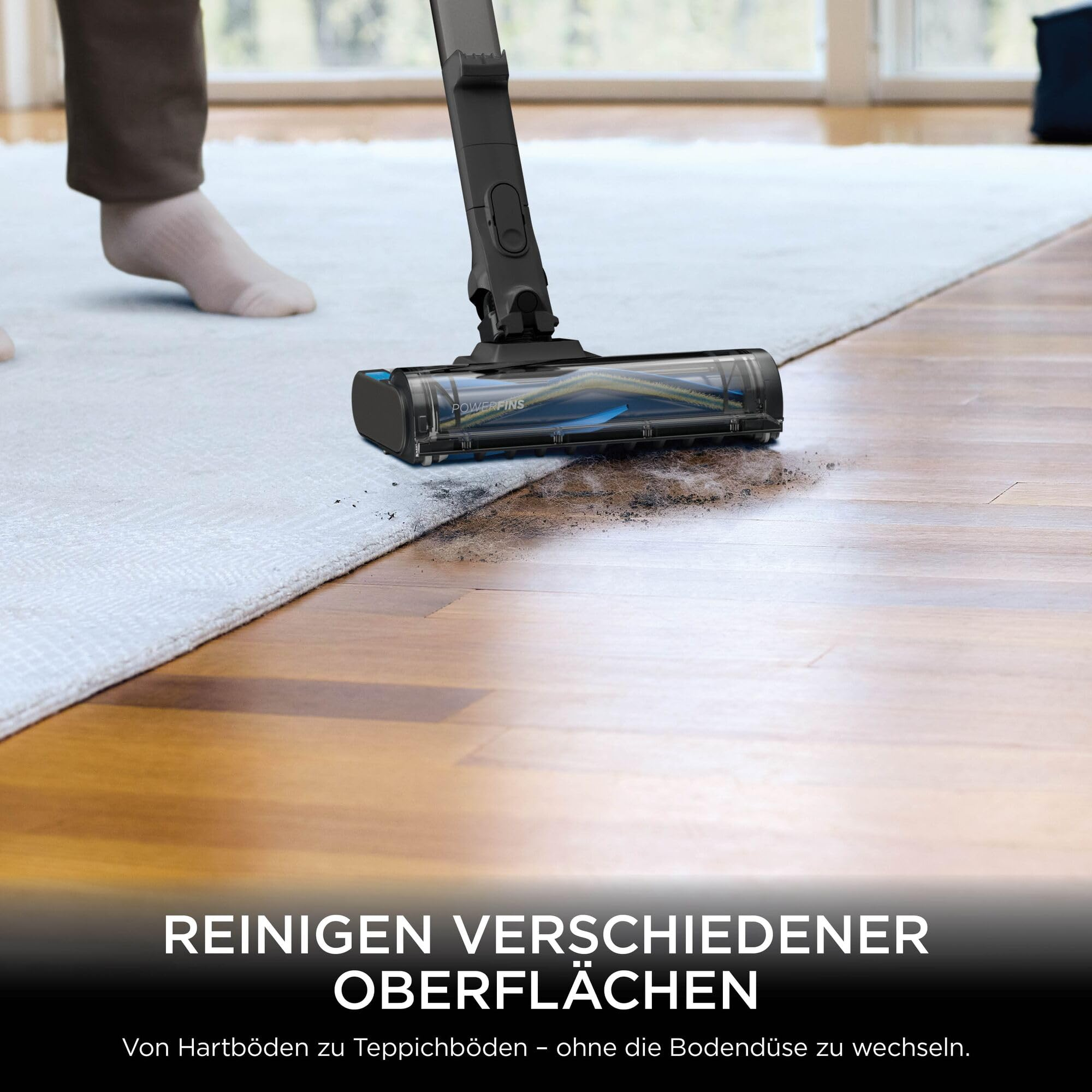 Ein Staubsauger reinigt Schmutz von Holzboden und Teppich.