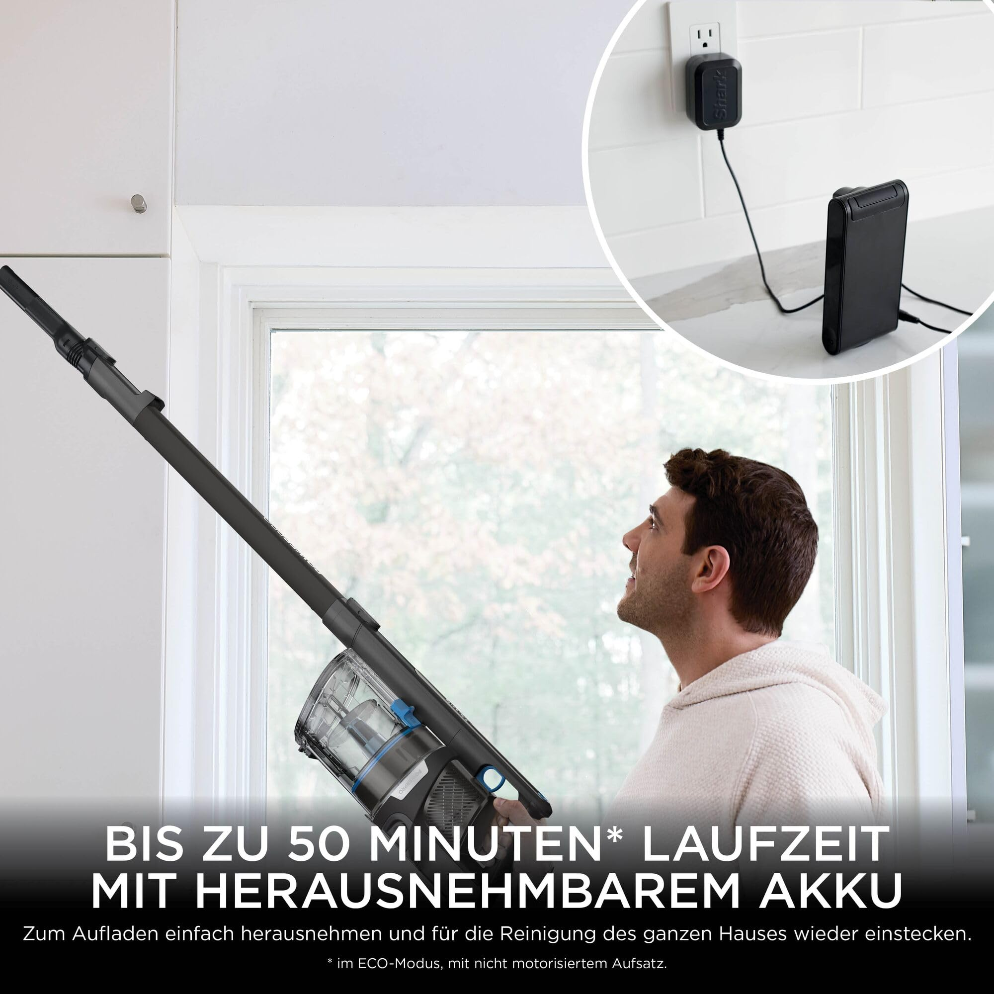 Ein Mann benutzt einen kabellosen Staubsauger, der Akku wird separat an der Wand geladen.