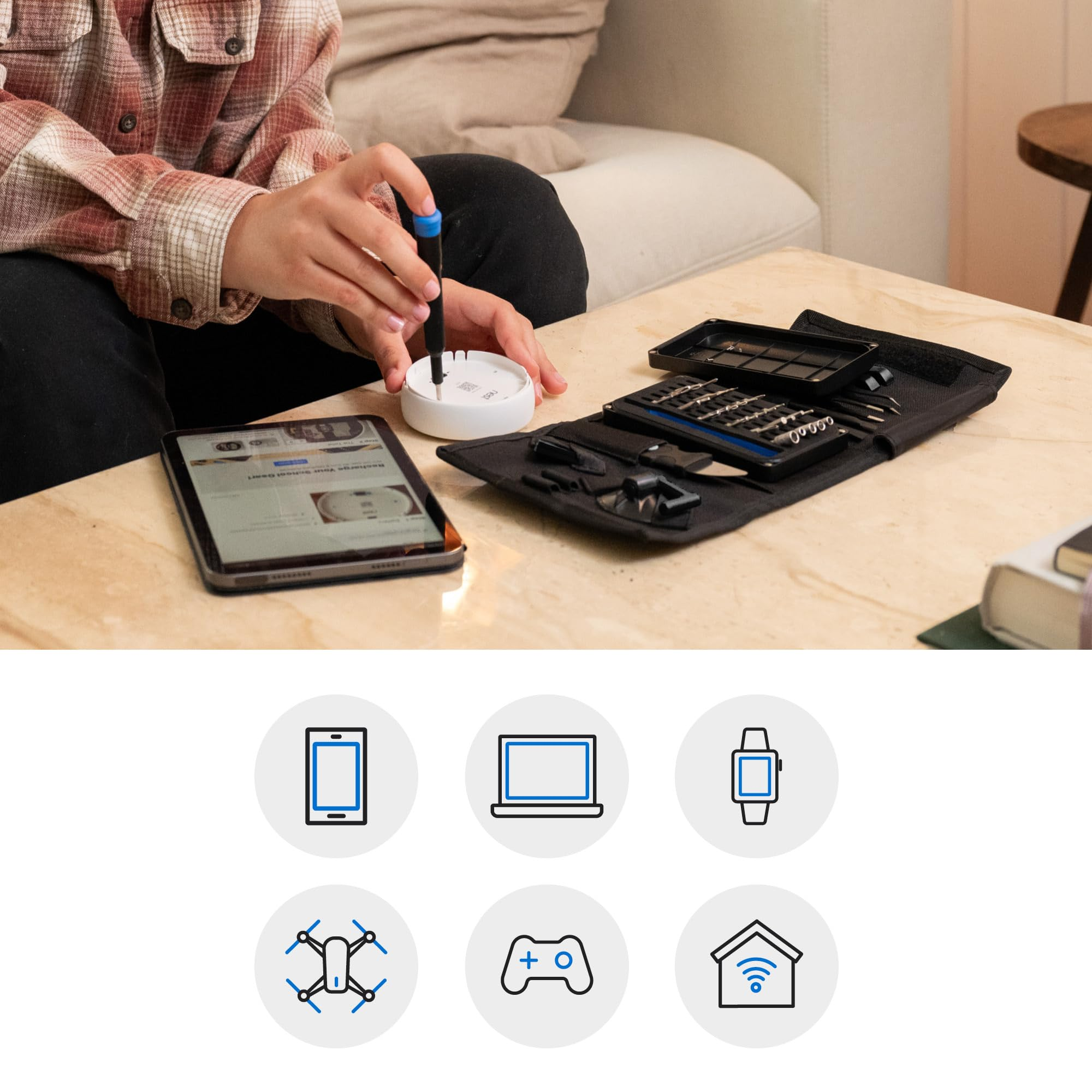 Persona ripara un dispositivo smart bianco con un cacciavite accanto a un tablet e un set.