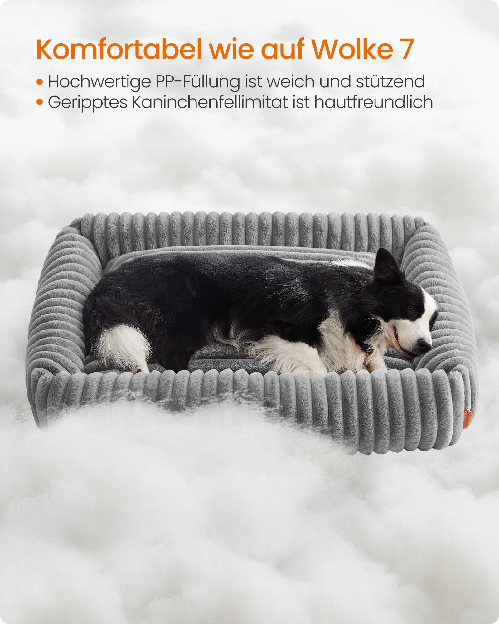Un cane bianco e nero dorme comodamente in una soffice cuccia grigia su cuscini bianchi.