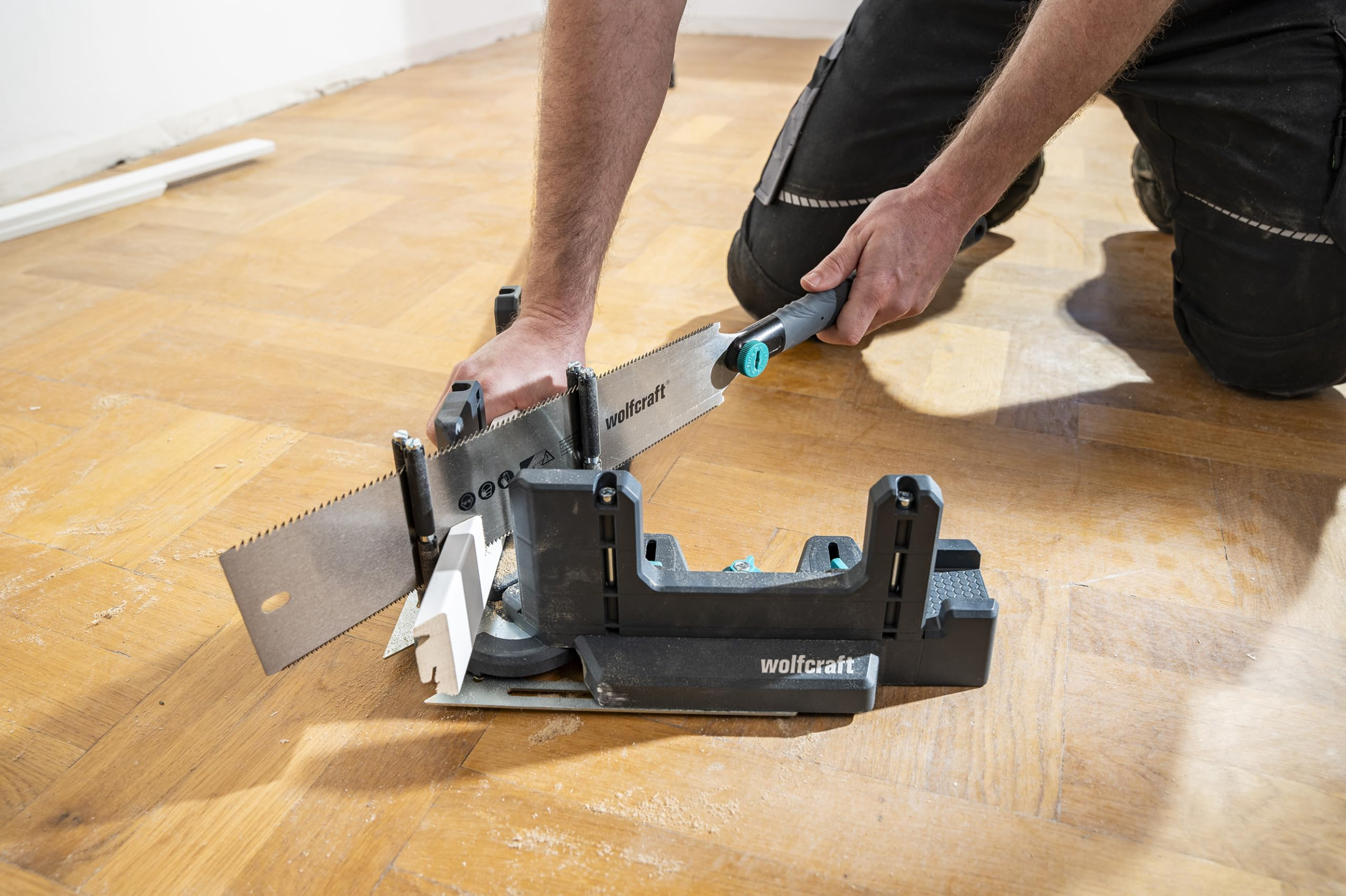 Ein Handwerker nutzt eine Wolfcraft-Gehrungssäge, um Holz auf einem Parkettboden zu schneiden.