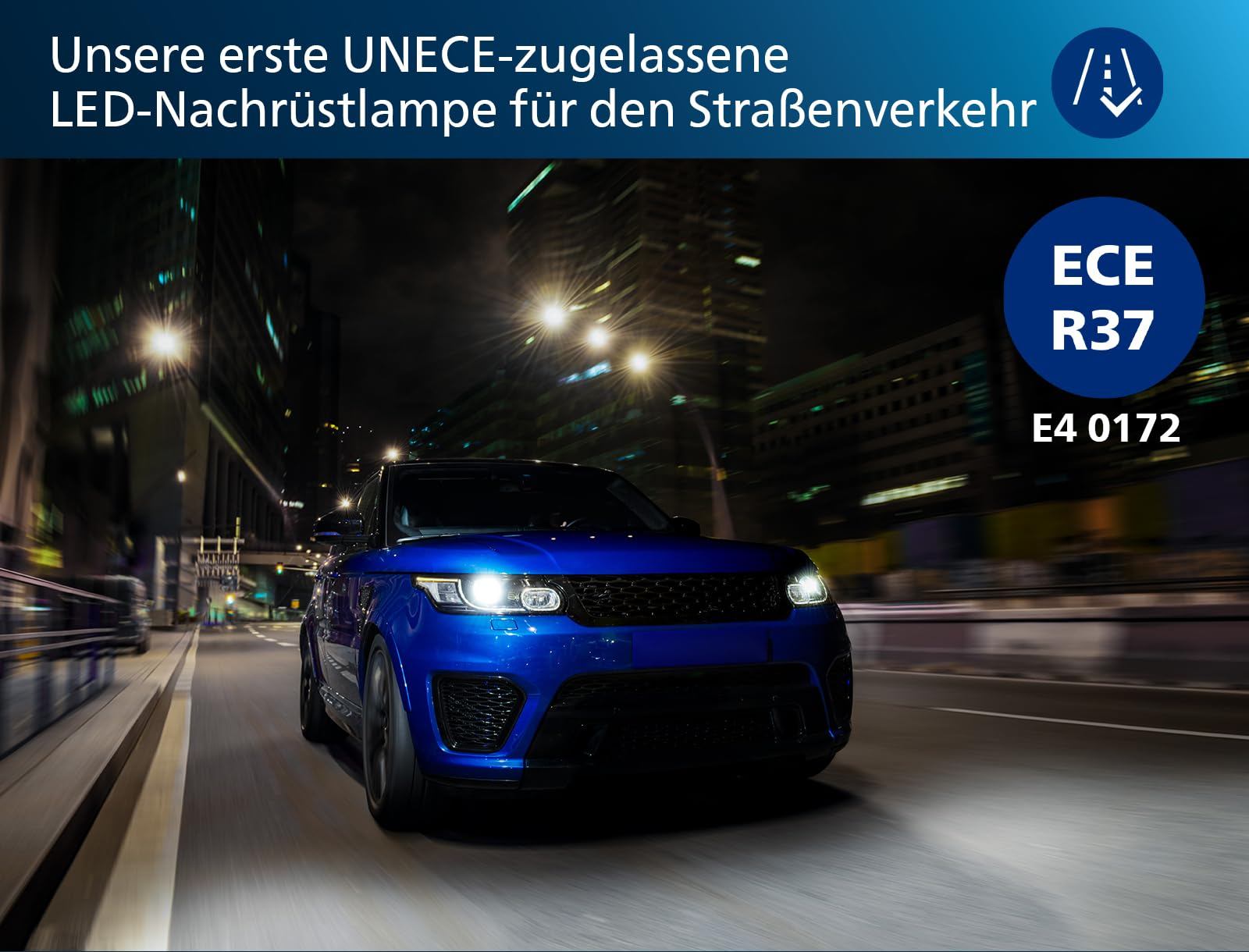 Un SUV bleu roule la nuit sur une rue de ville illuminée, phares allumés.