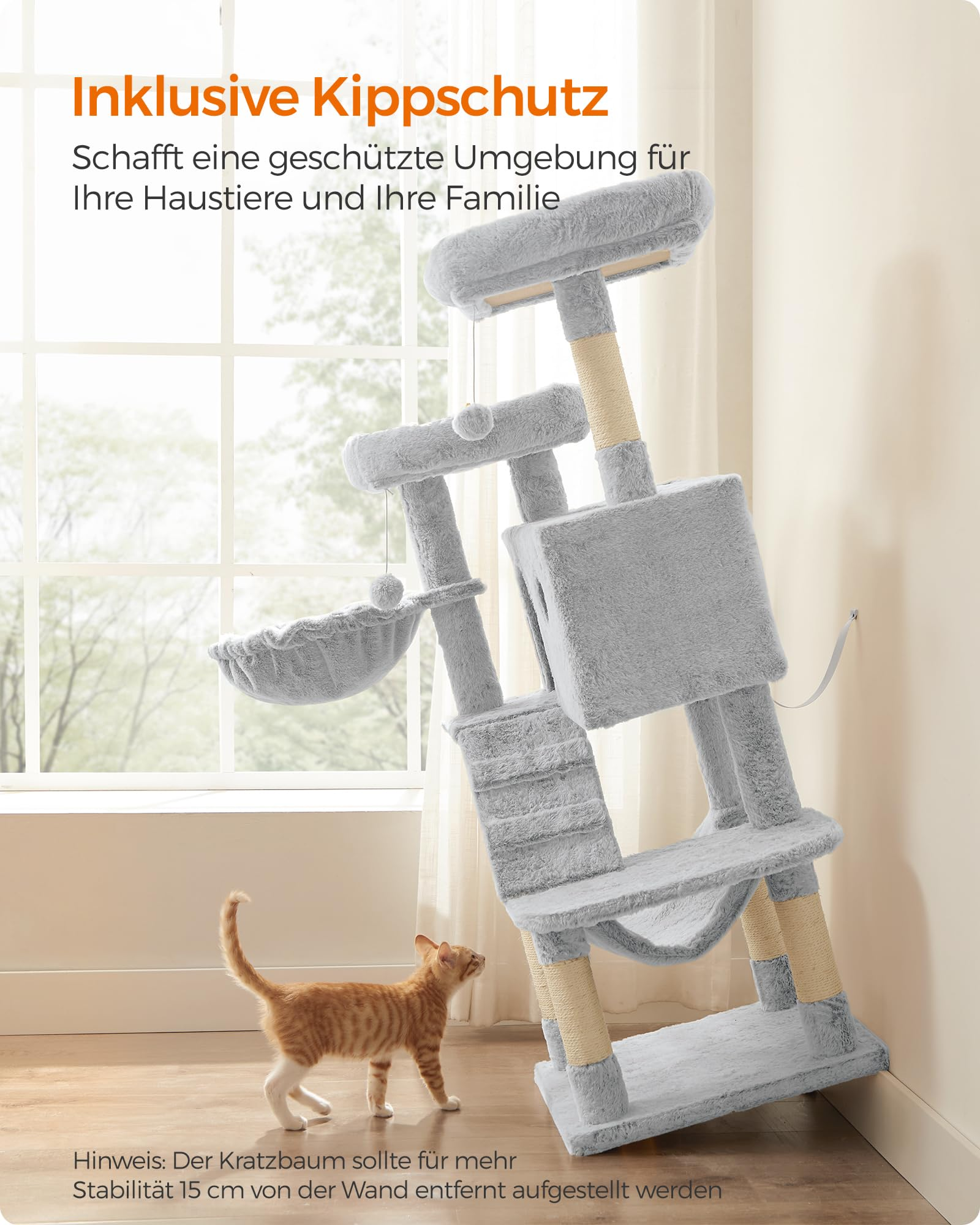 Un grande tiragraffi grigio con attacco di sicurezza e un piccolo gatto arancione in una stanza luminosa.