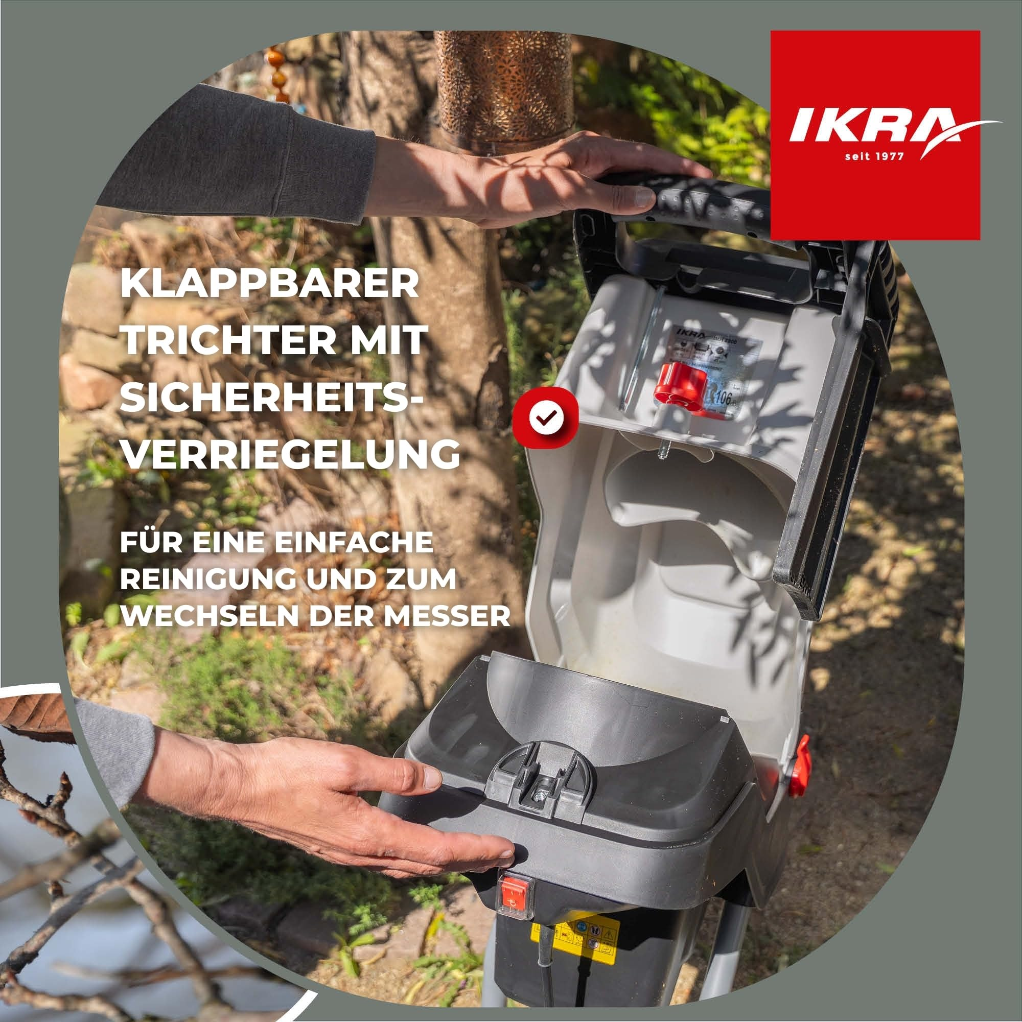Hände öffnen einen klappbaren Trichter an einem grau-schwarzen Gartenhäcksler.
