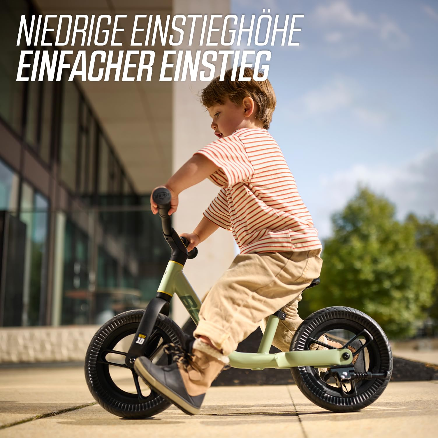 Bambino che guida una balance bike verde all'aperto.