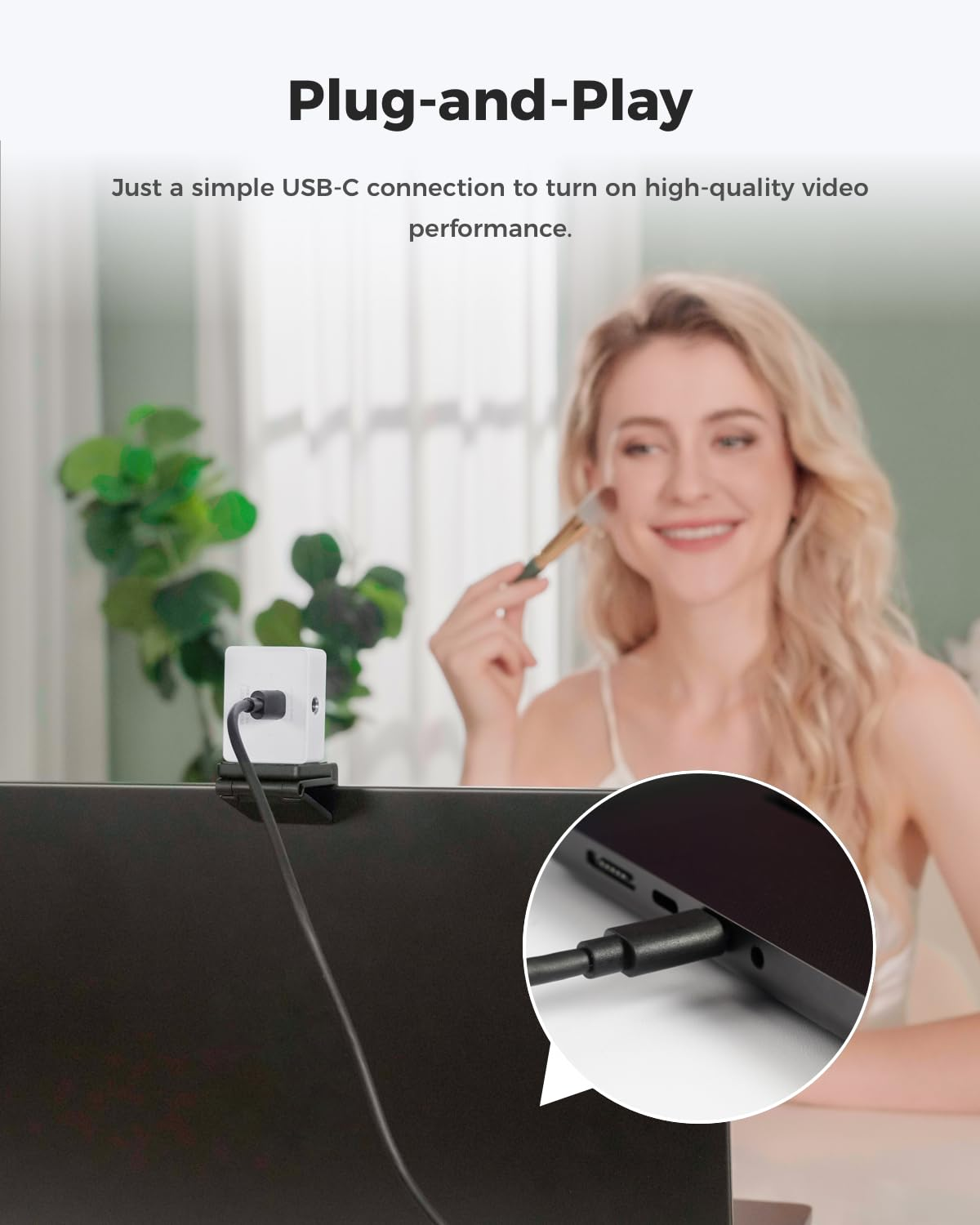 Una webcam bianca su un laptop con cavo USB-C, accanto a una donna sorridente con un pennello.