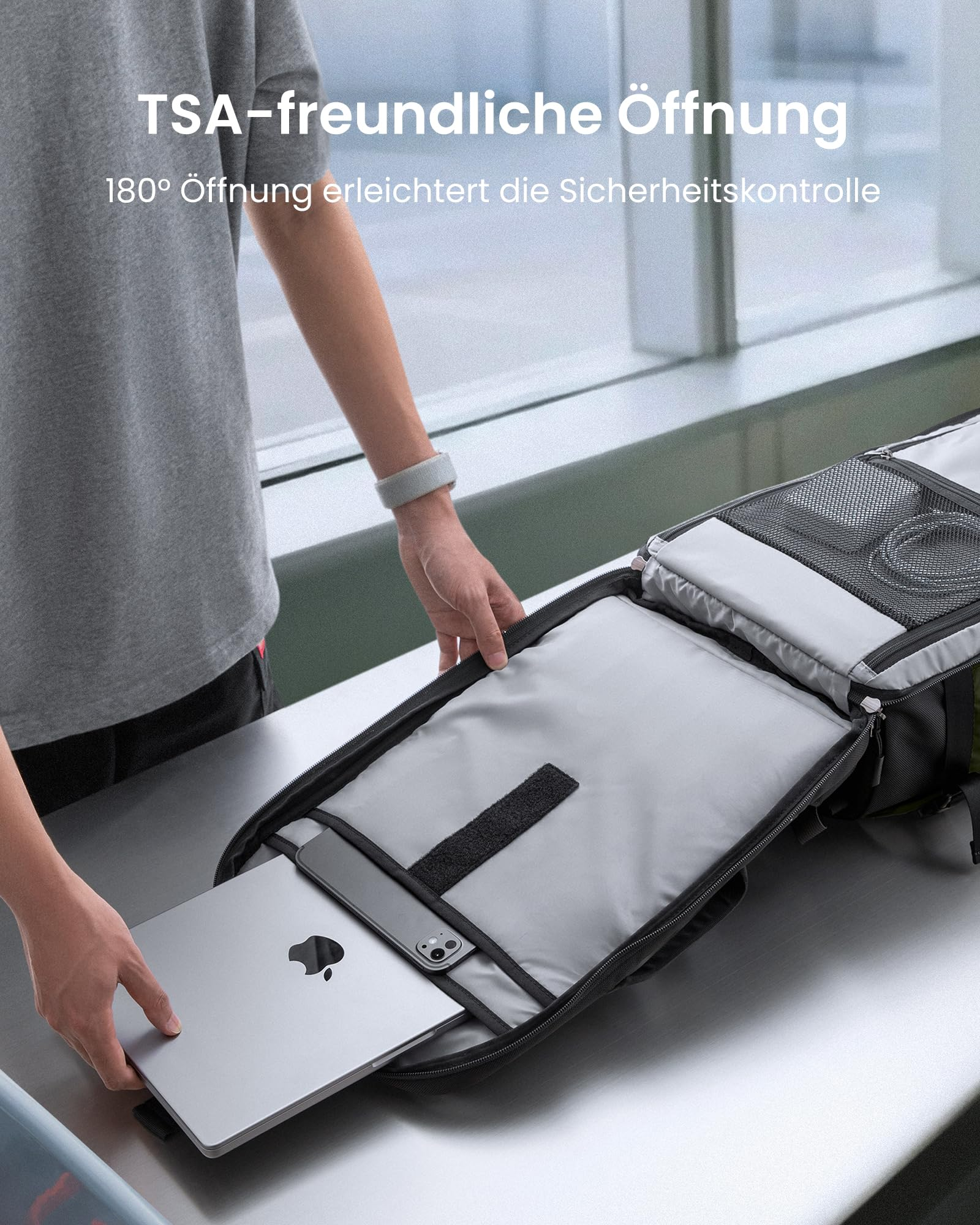 Ein Mann packt einen Laptop in einen flach geöffneten Rucksack.
