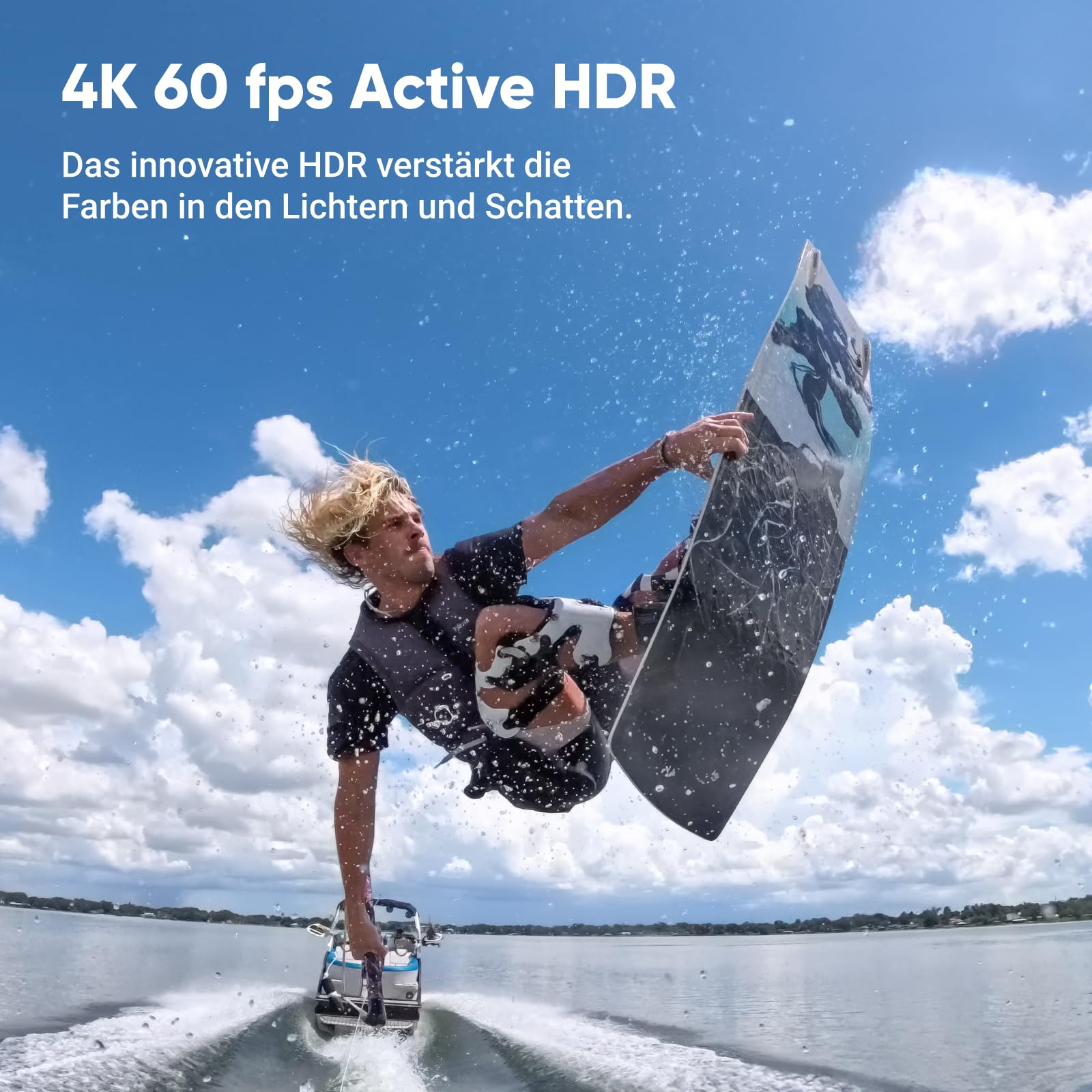 Un wakeboarder saute haut dans les airs au-dessus d'un lac, avec un bateau en arrière-plan sous un ciel bleu.