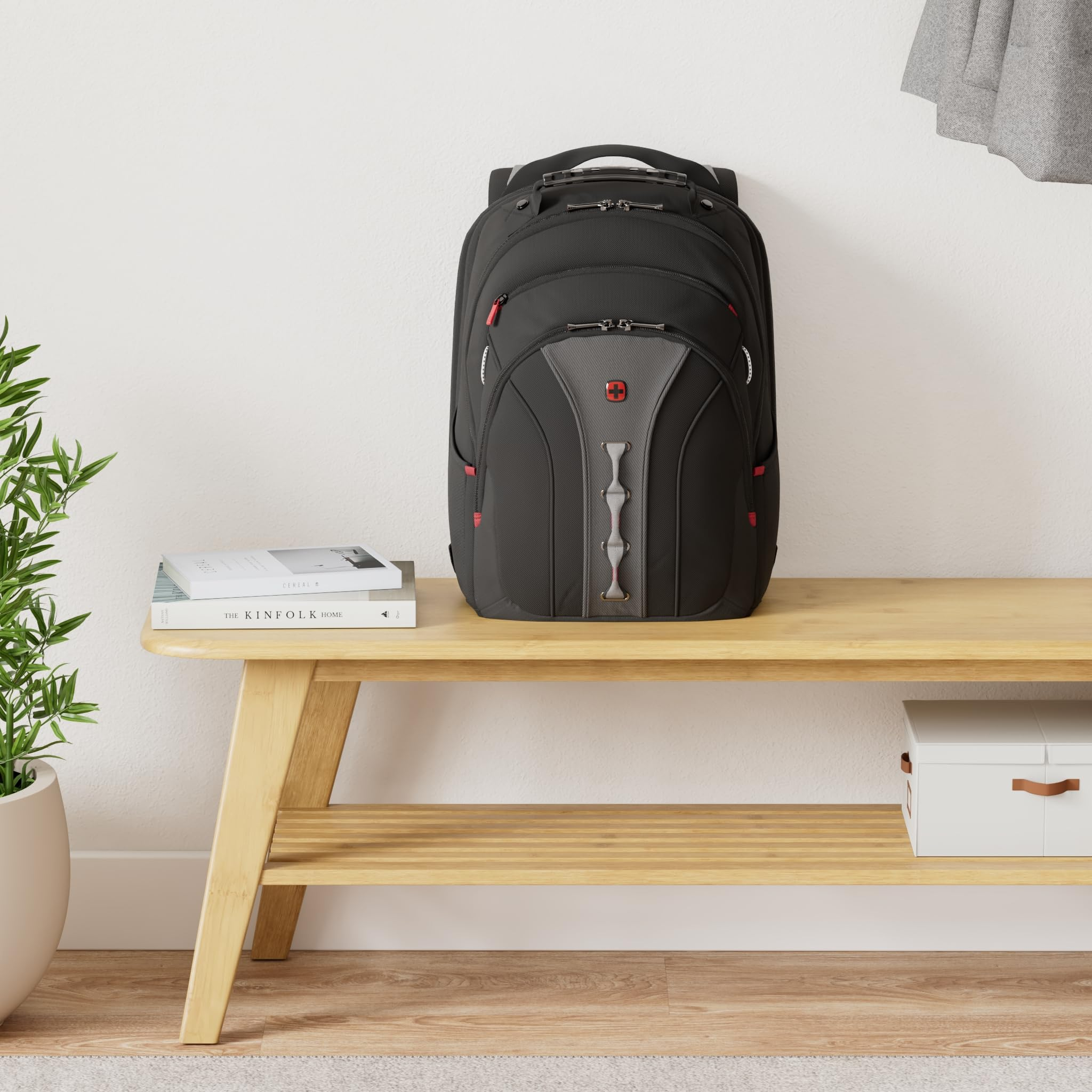 Ein schwarzer Rucksack steht auf einer Holzsitzbank mit Büchern und einer weißen Box.
