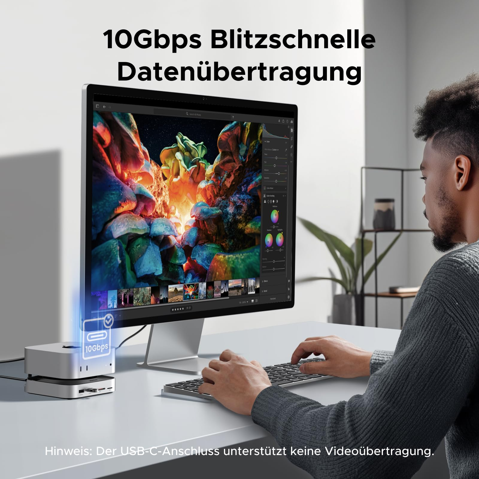 Ein Mann tippt auf einer Tastatur vor einem großen Bildschirm. Links steht ein silbernes Hub-Gerät.