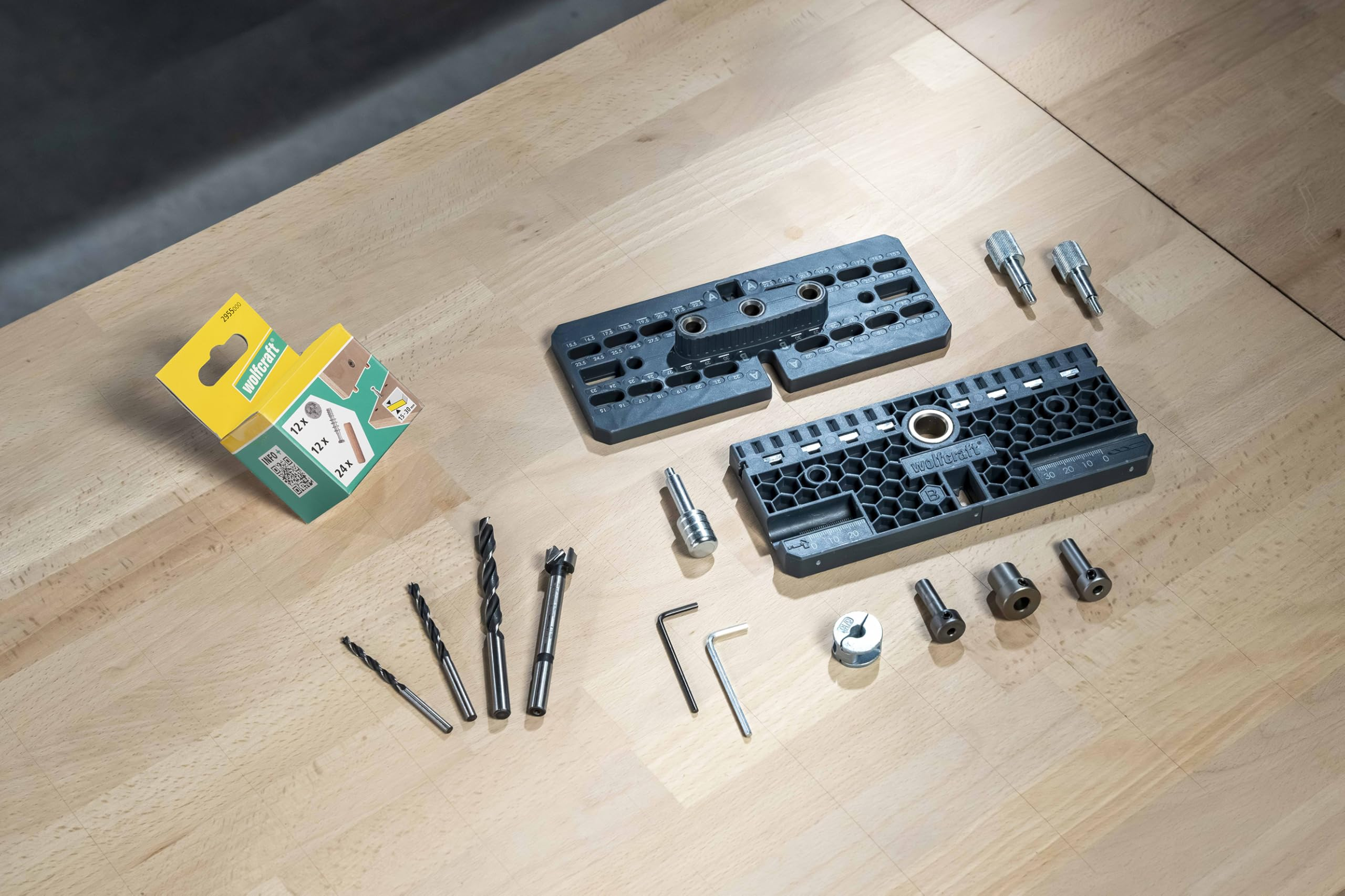 Wolfcraft Dübelset mit Bohrschablone, Bohrer, Stiften und Zubehör auf einer Werkbank.