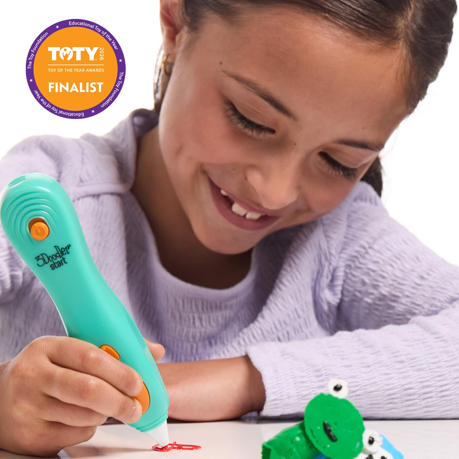 Une fille souriante utilise un stylo 3D turquoise pour dessiner des lignes rouges.