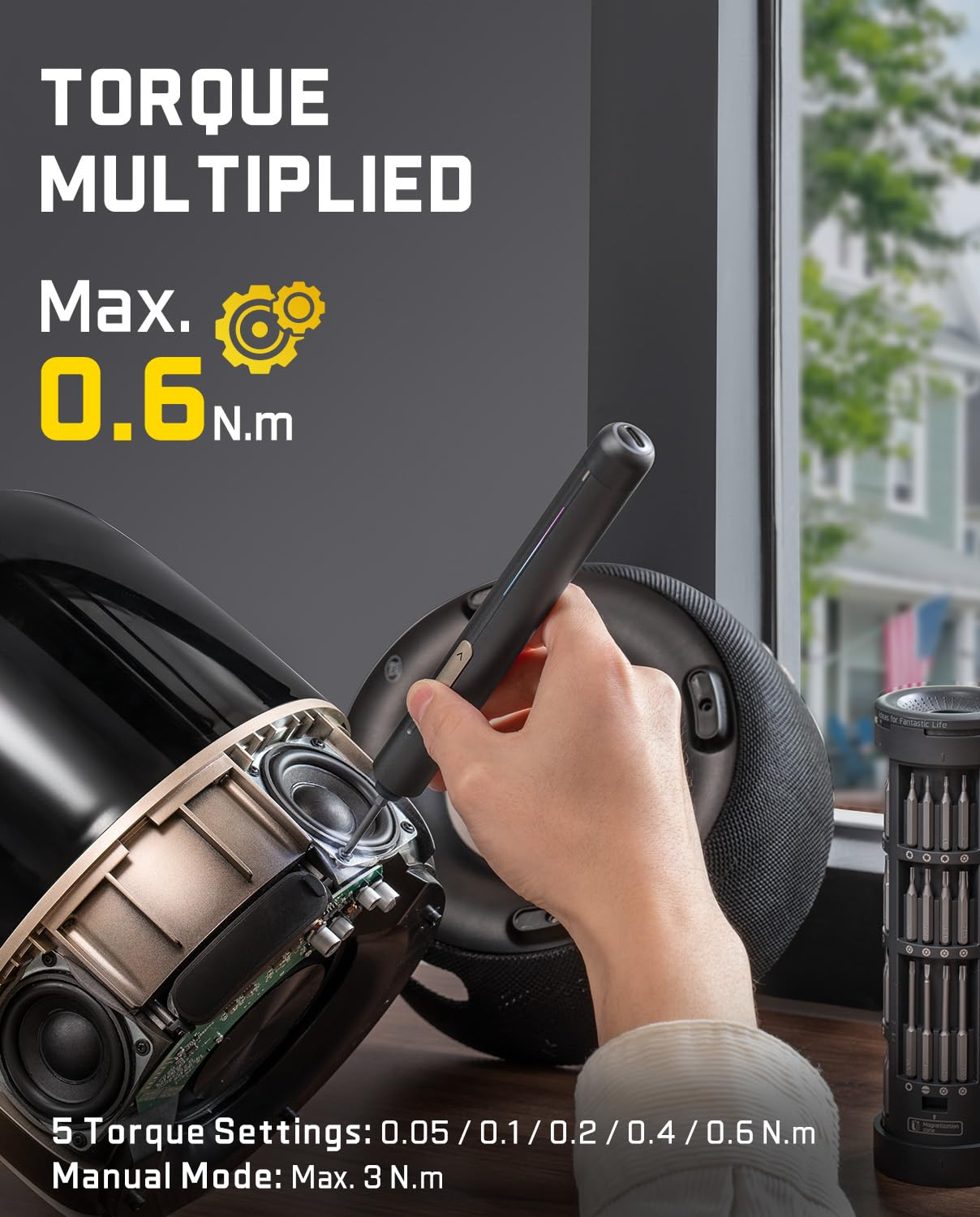 Mano che tiene un cacciavite elettrico per riparare un dispositivo audio aperto. Testo mostra la coppia.