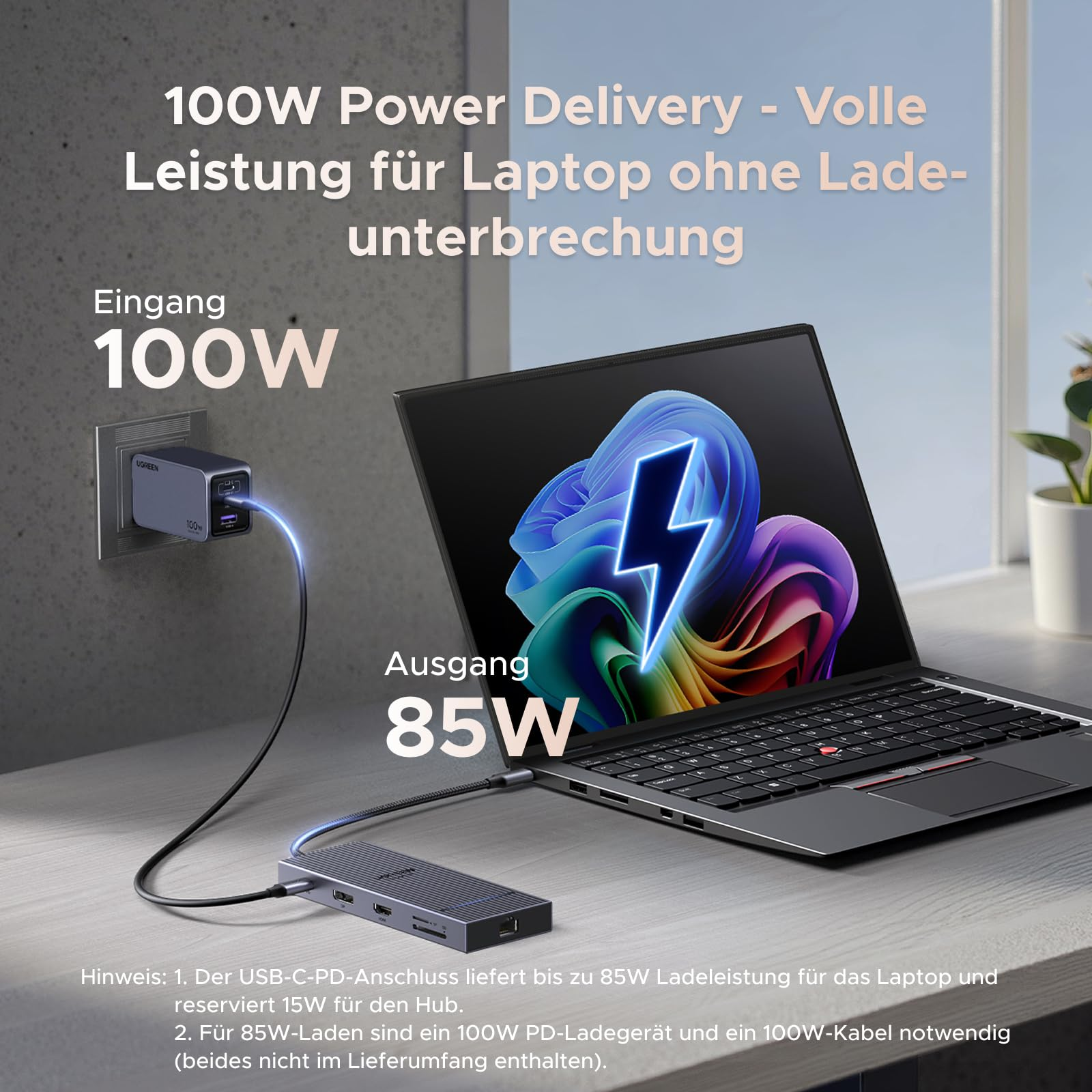 Un chargeur mural de 100W alimente un ordinateur portable sur un bureau via un câble et un concentrateur USB.