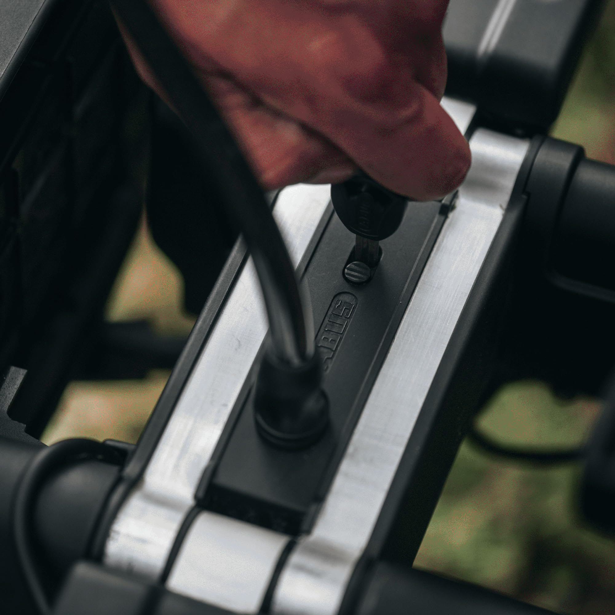 Une main insère une clé dans un antivol de vélo sur un cadre en métal.