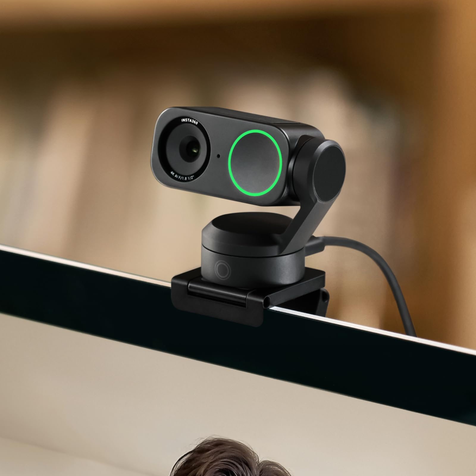 Una webcam Insta360 nera con luce verde è montata su un monitor per computer.