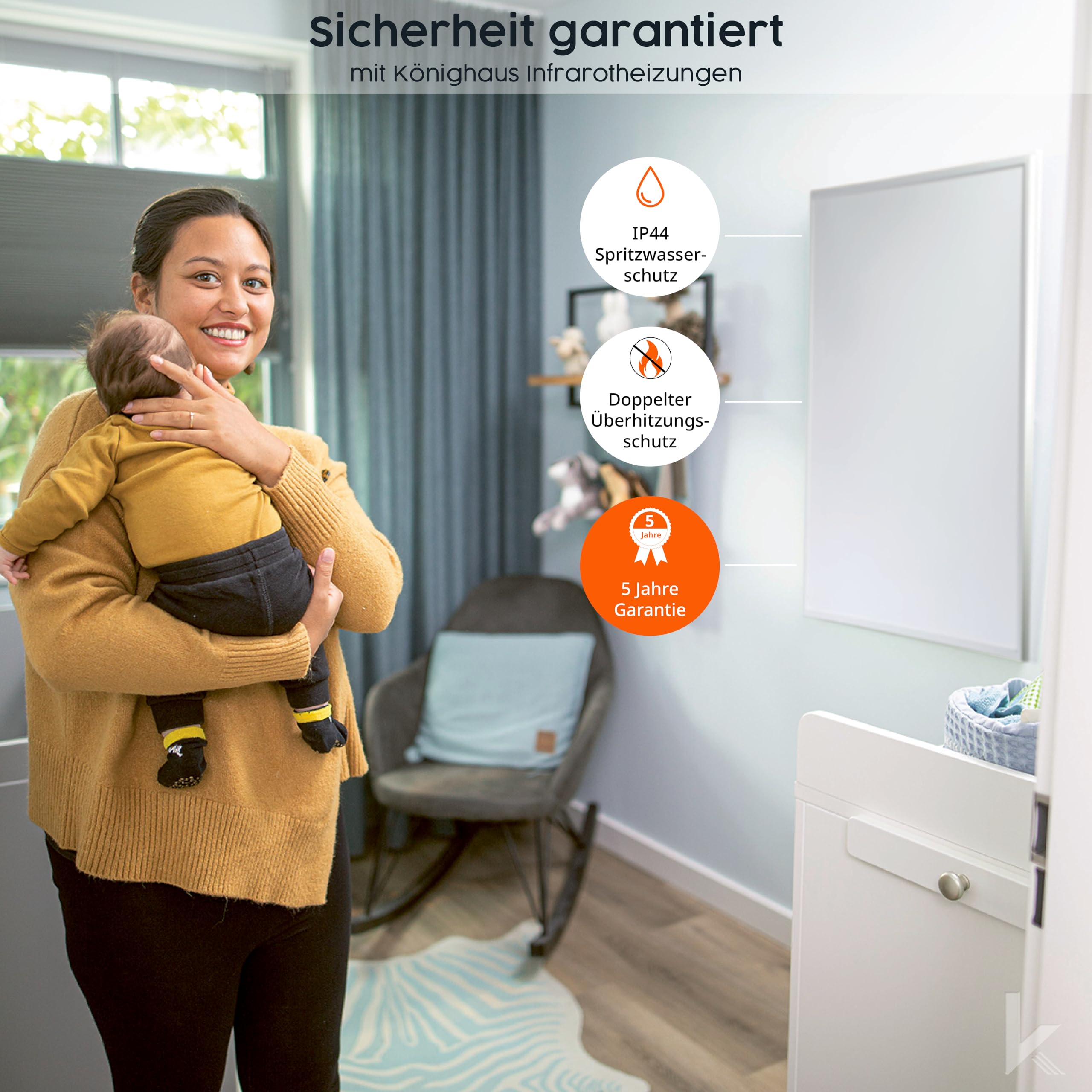 Eine Frau hält lächelnd ein Baby im Arm, daneben an der Wand hängt ein Infrarotheizpanel.