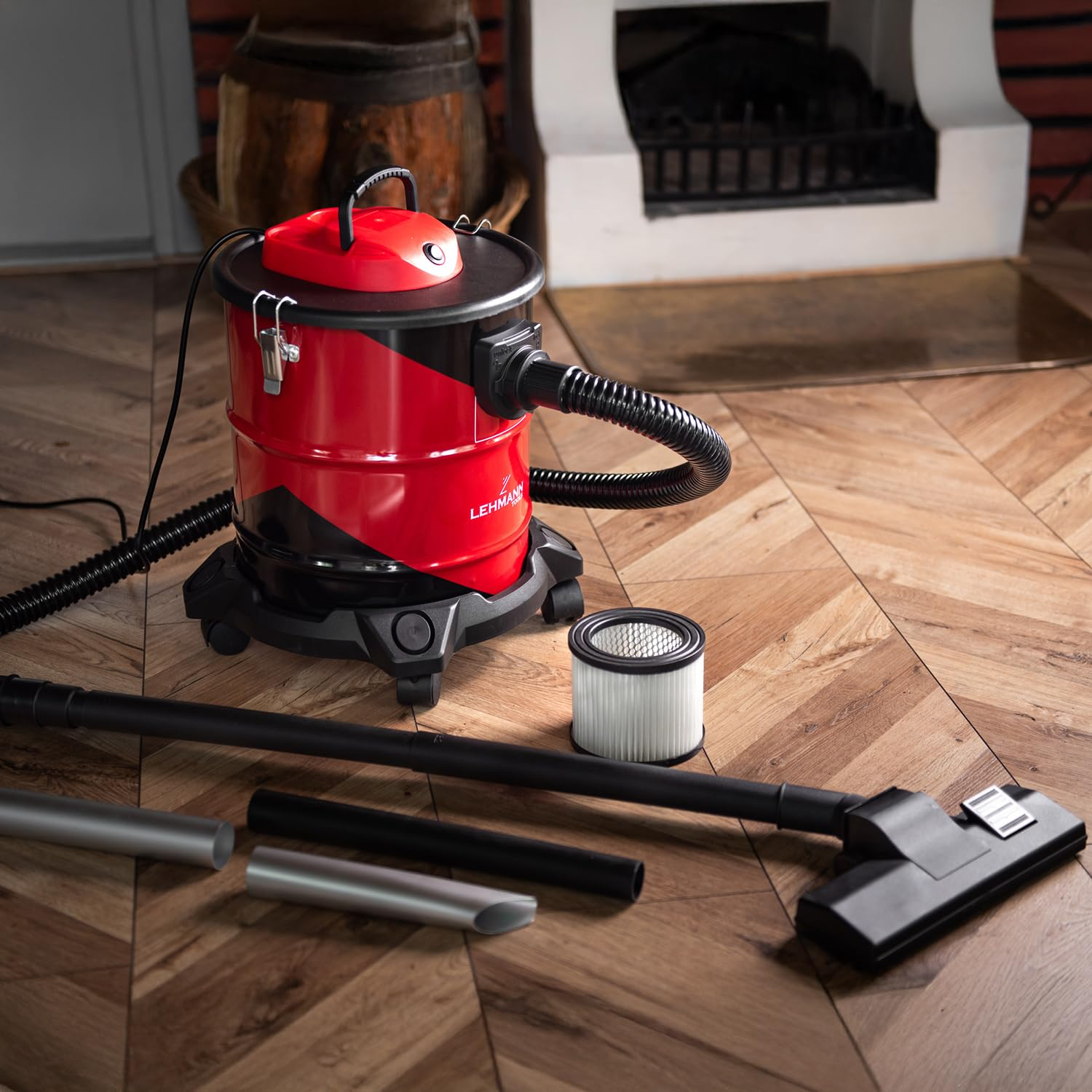 Un aspirapolvere a umido e a secco rosso e nero con accessori su un pavimento in legno.