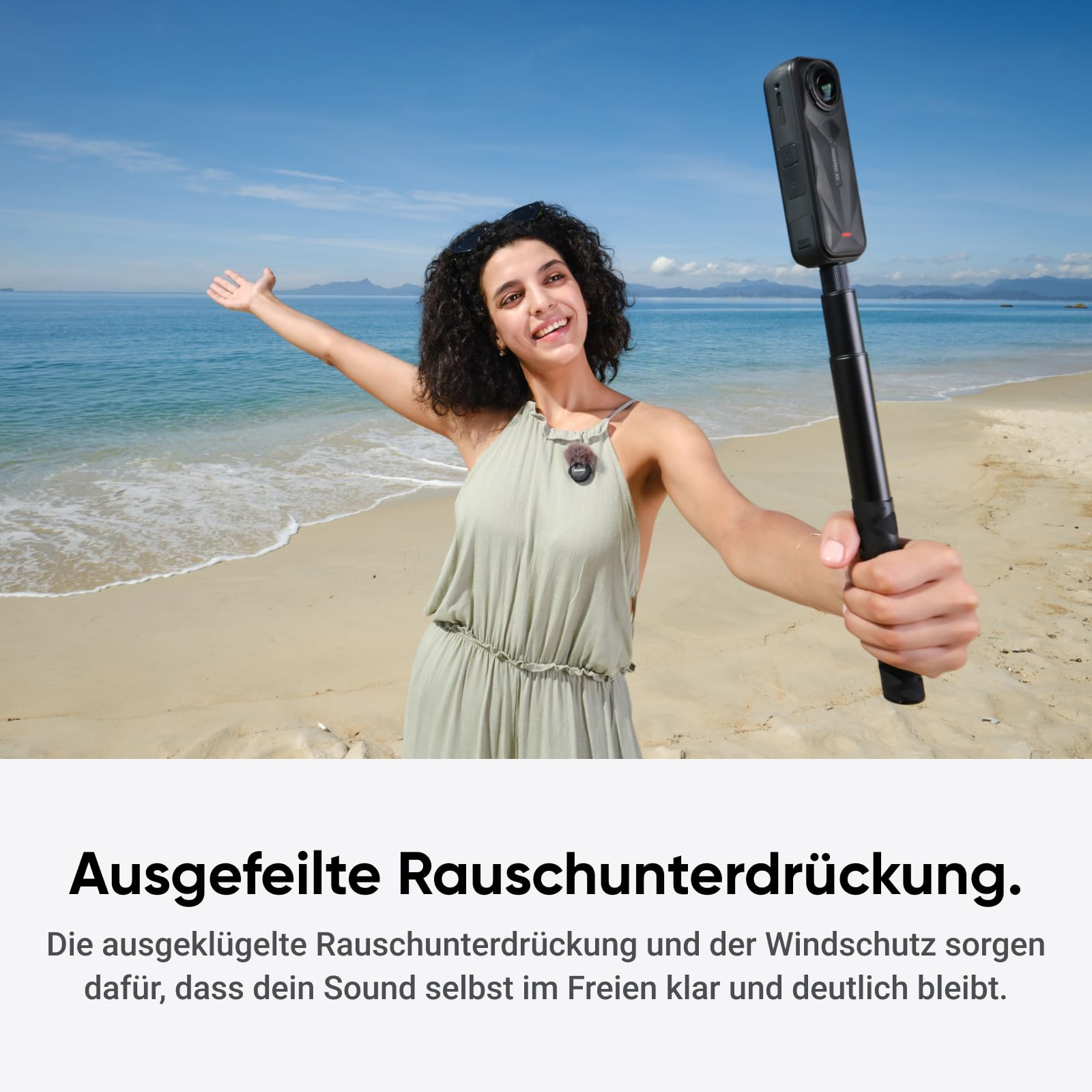 Frau mit Kamera am Strand vor dem Meer.