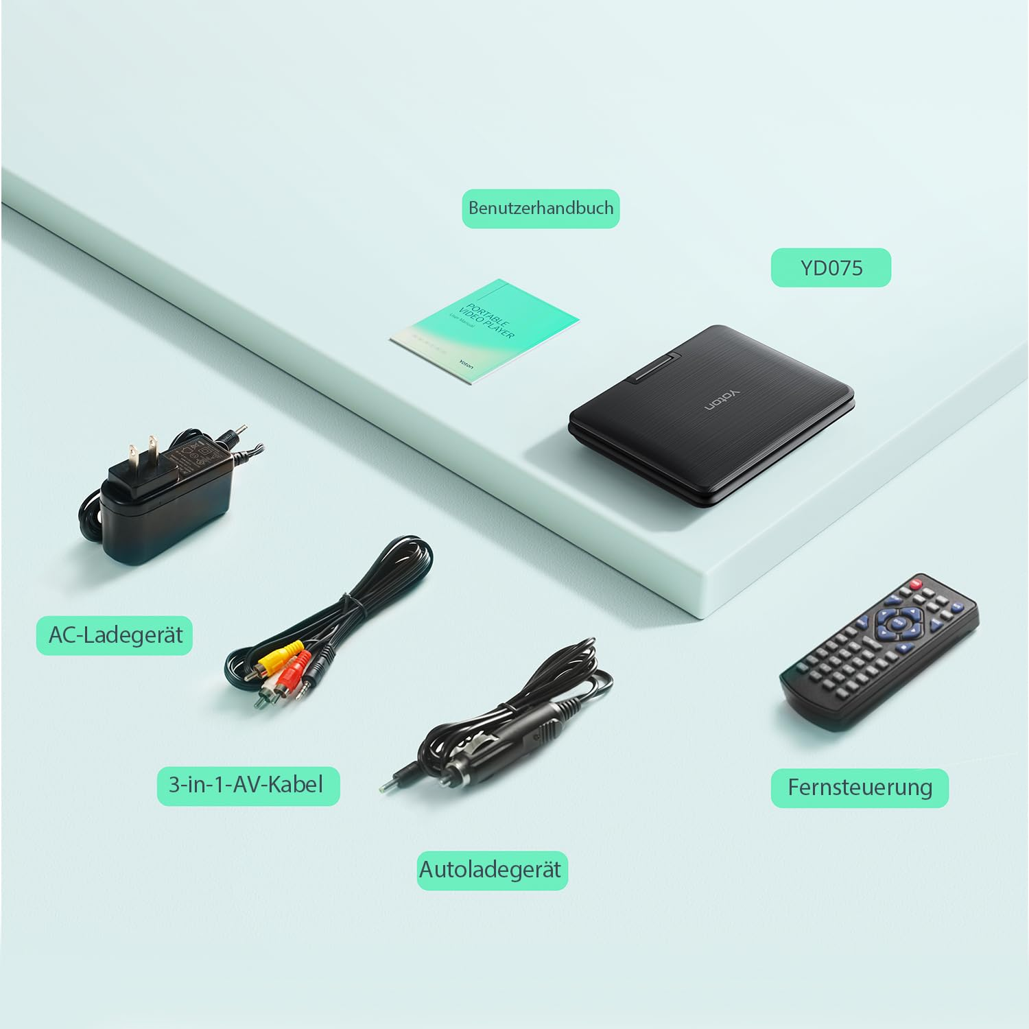 Ein tragbarer DVD-Player, eine Fernbedienung, Kabel, ein Netzteil und ein Handbuch liegen auf einer grünen Ablage.