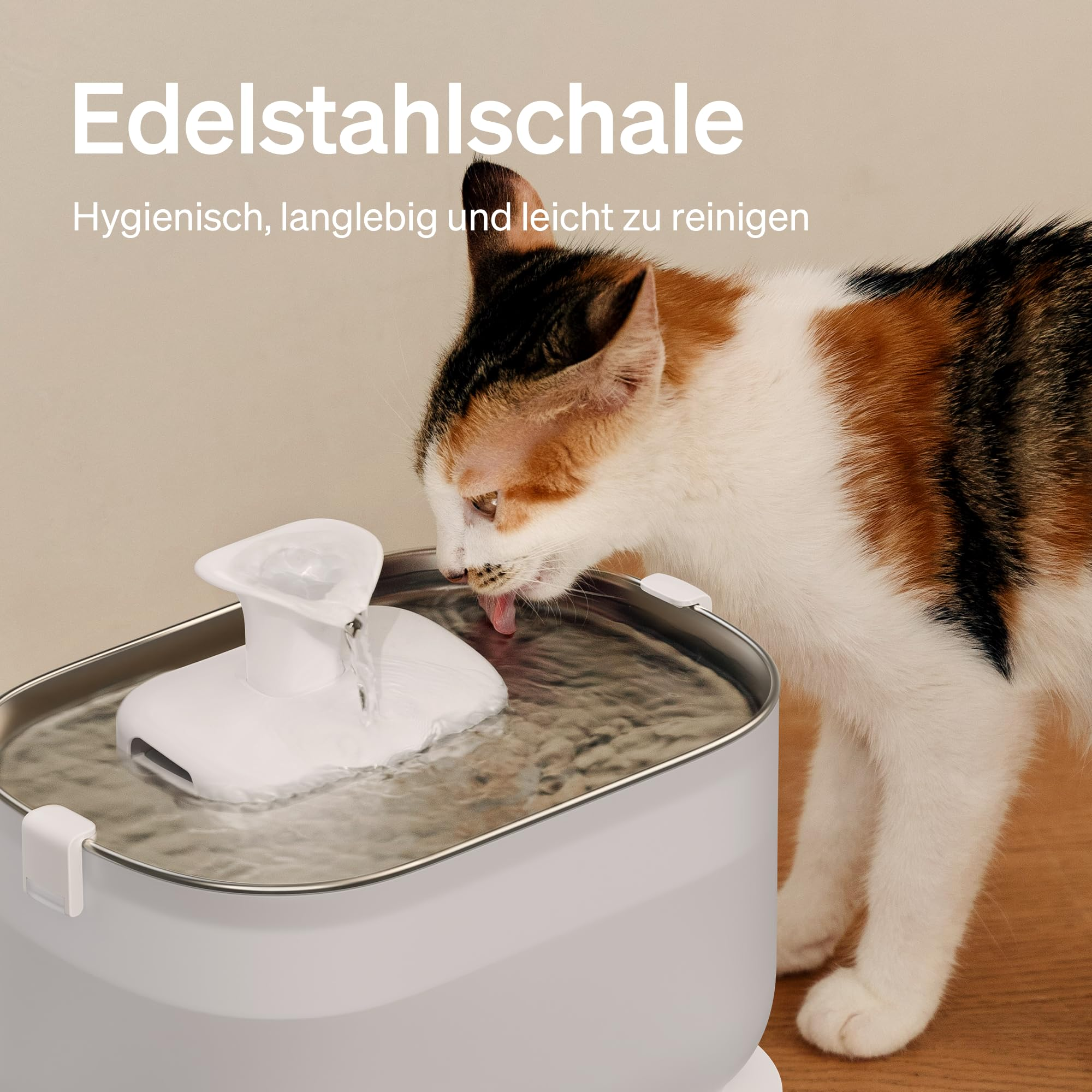 Eine dreifarbige Katze trinkt frisches Wasser aus einem modernen, edelstahlfarbenen Haustierbrunnen.