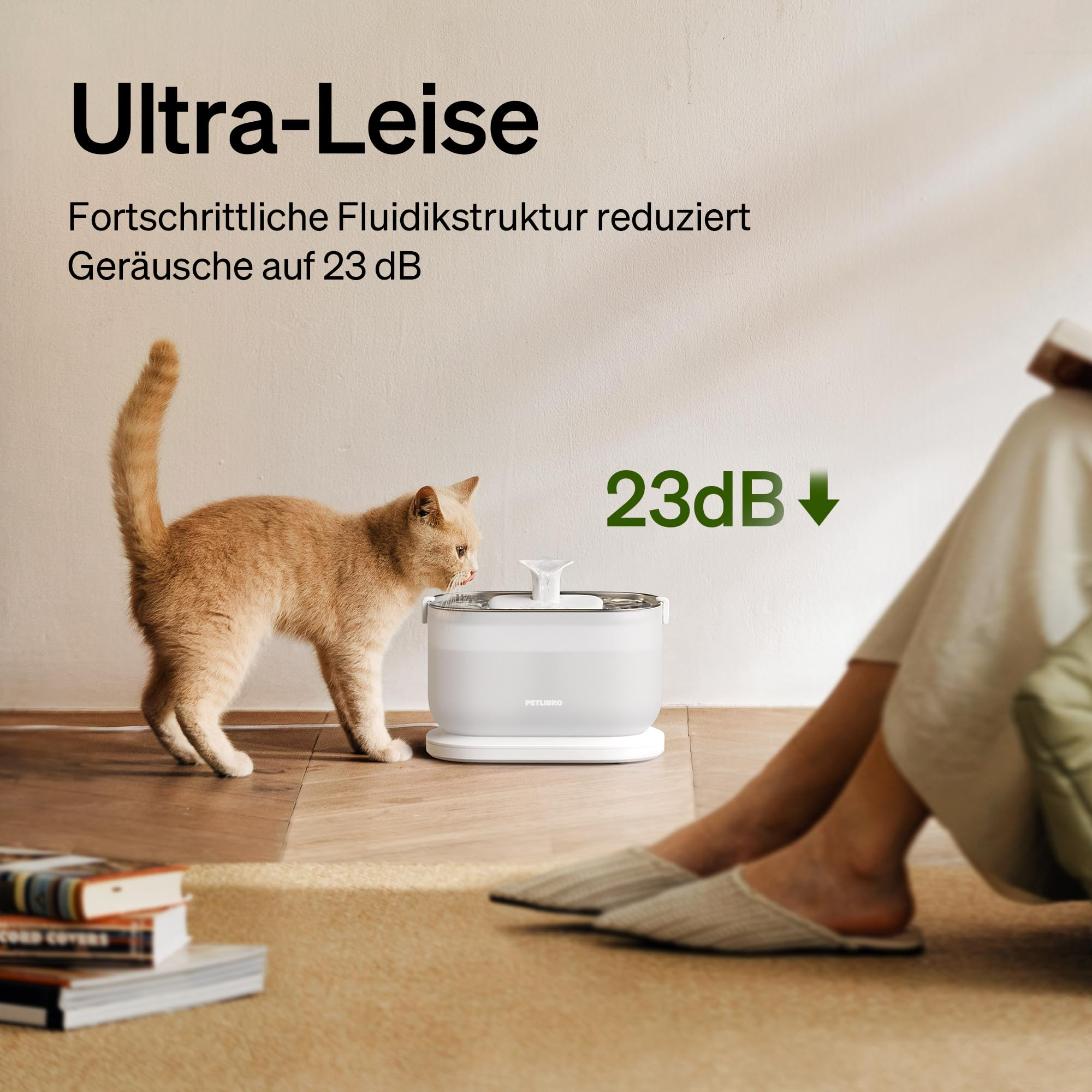 Eine orange Katze trinkt aus einem leisen Wasserspender in einem Wohnzimmer.