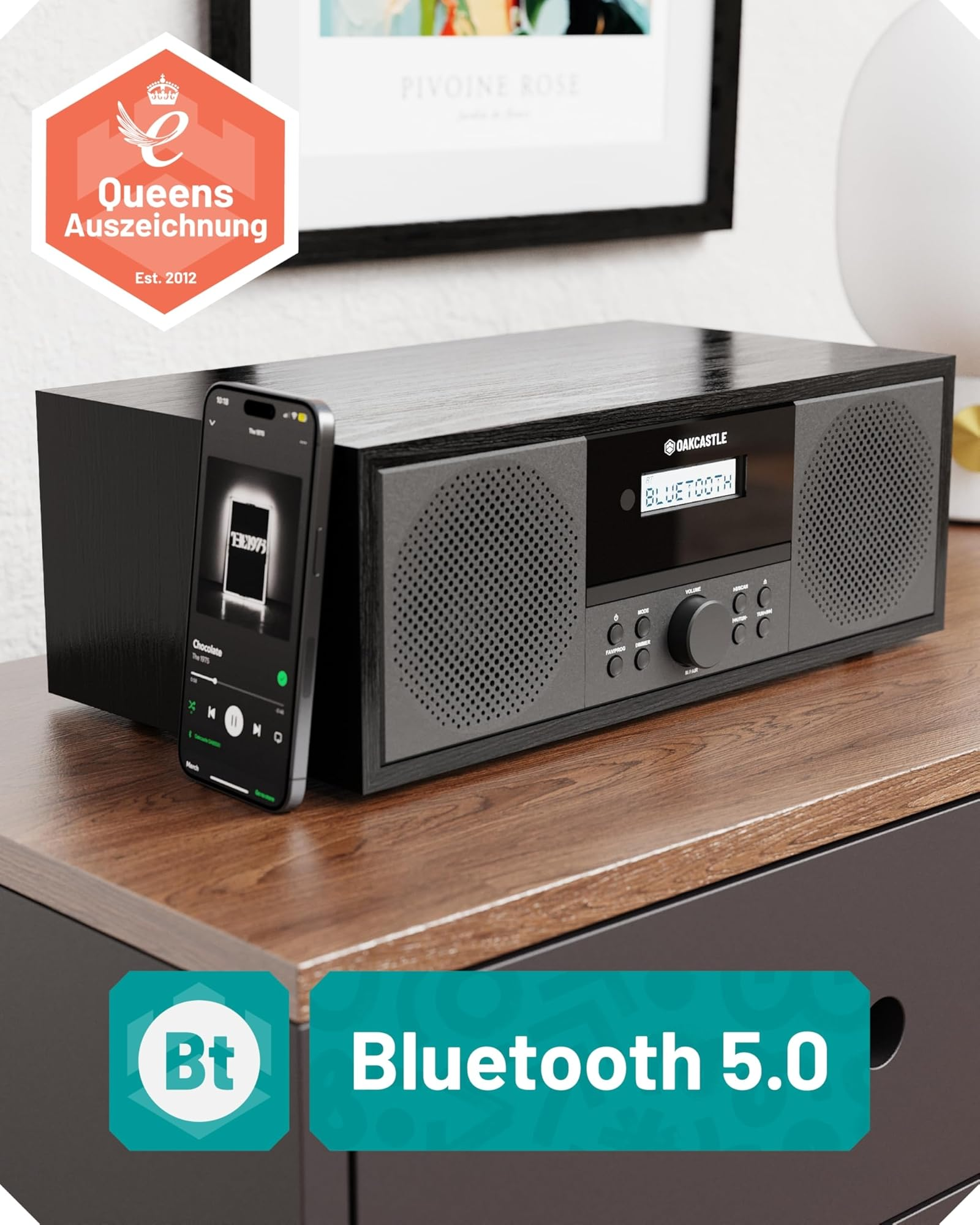 Ein schwarzes Oakcastle-Radio mit Bluetooth und ein Smartphone auf einem Holztisch.