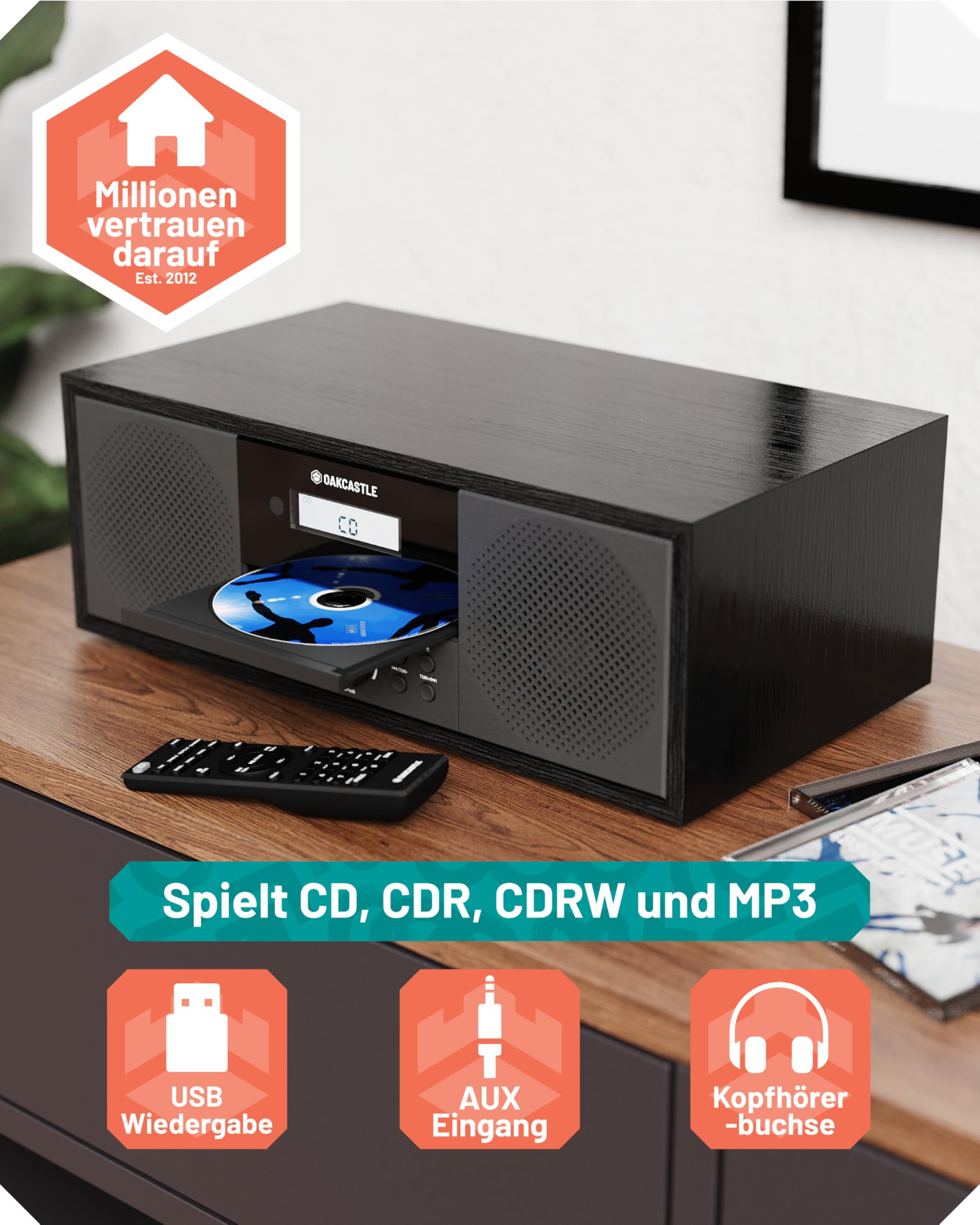 Schwarzes Oakcastle Hifi-System mit offener CD-Schublade, Fernbedienung und Icons für USB-, AUX- und Kopfhöreranschlüsse.