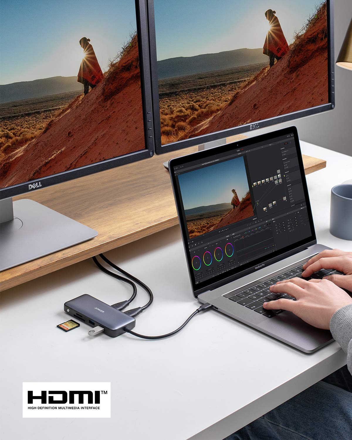 Una scrivania con laptop, due monitor, un hub USB-C e mani che digitano.