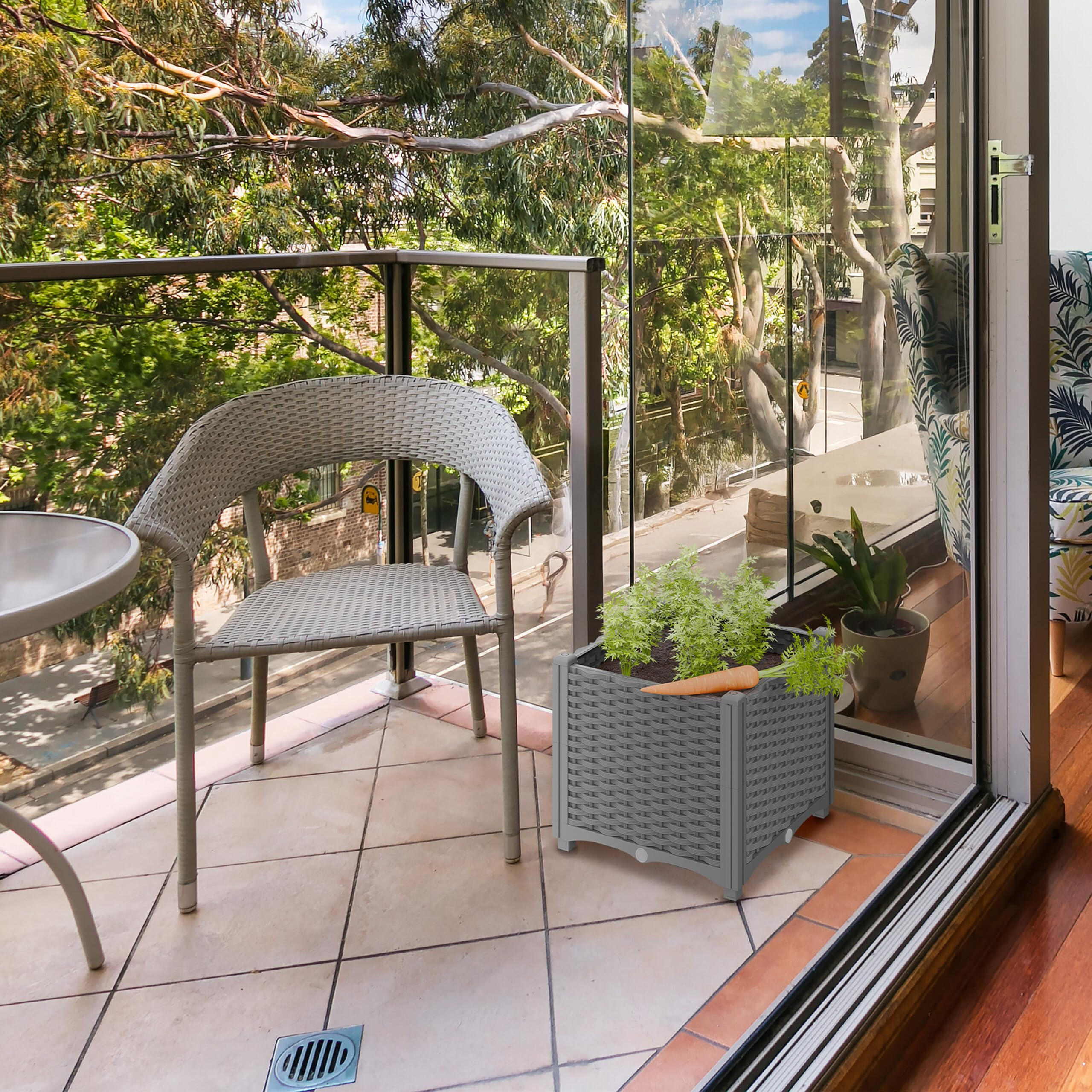 Balcon avec chaise grise, table d'appoint et jardinière de carottes, vue sur les arbres.