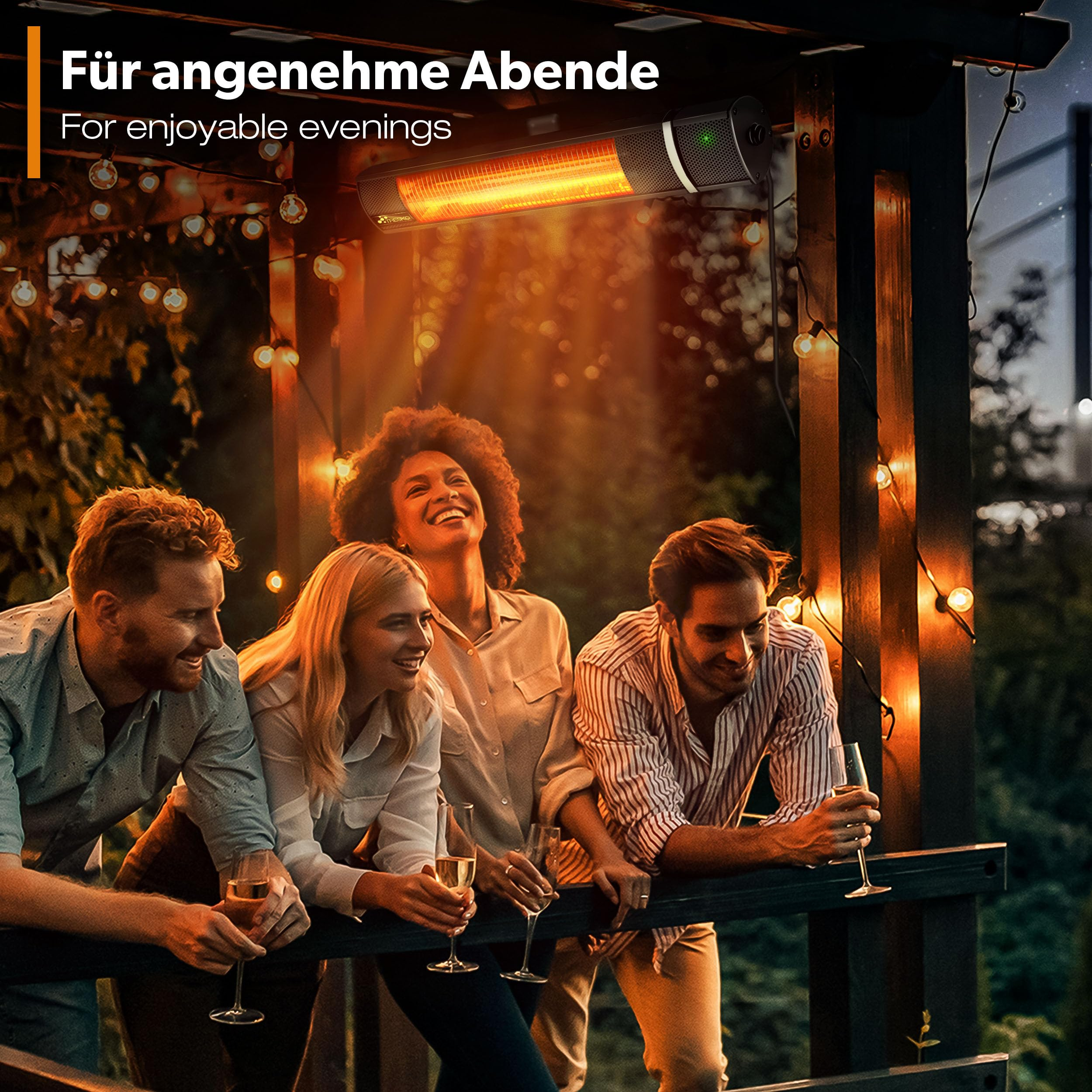 Vier Freunde lächeln unter einem Terrassenheizer und Lichterketten auf einem Balkon.