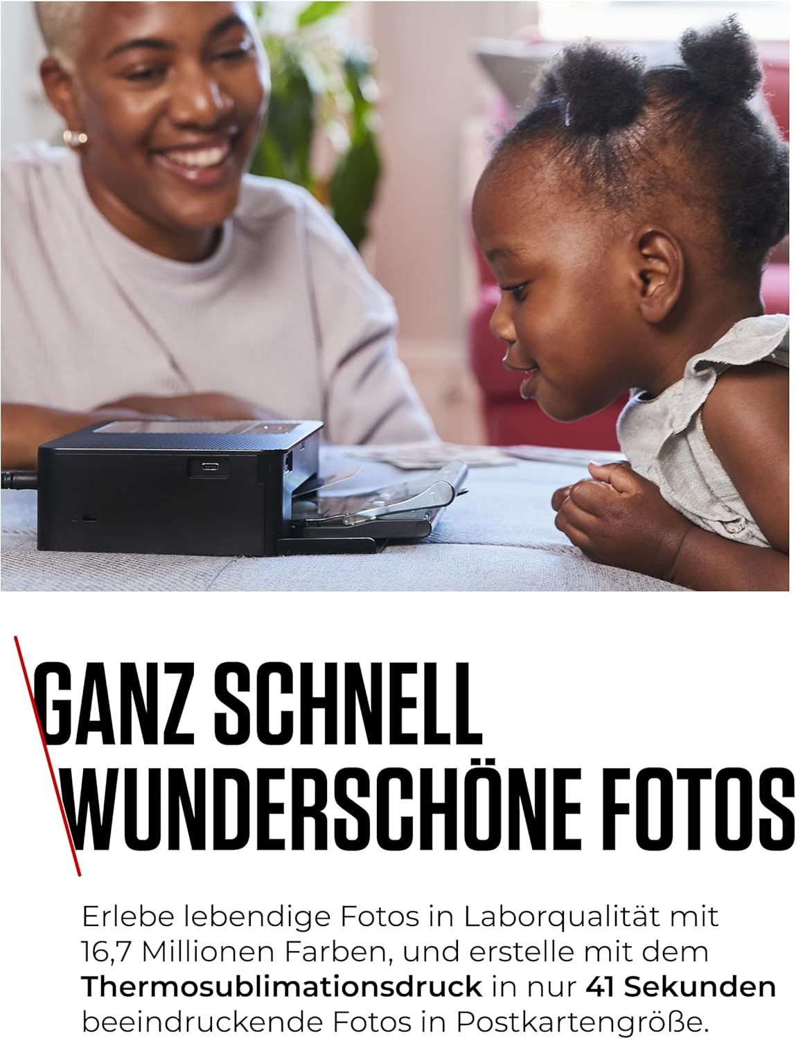 Eine Frau und ein kleines Mädchen schauen freudig auf einen kleinen schwarzen Drucker auf einem Tisch.