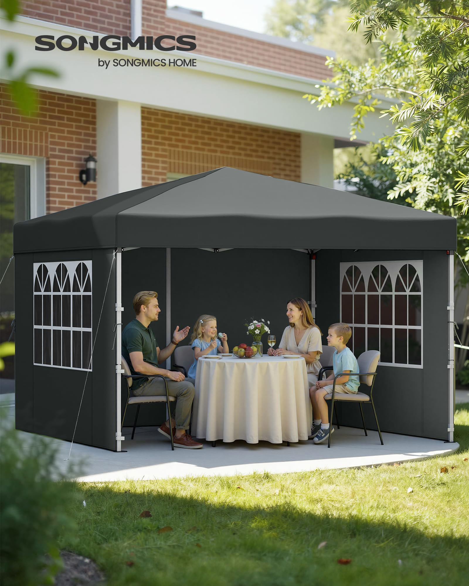 Eine Familie sitzt im Garten unter einem grauen Pavillon an einem gedeckten Tisch.