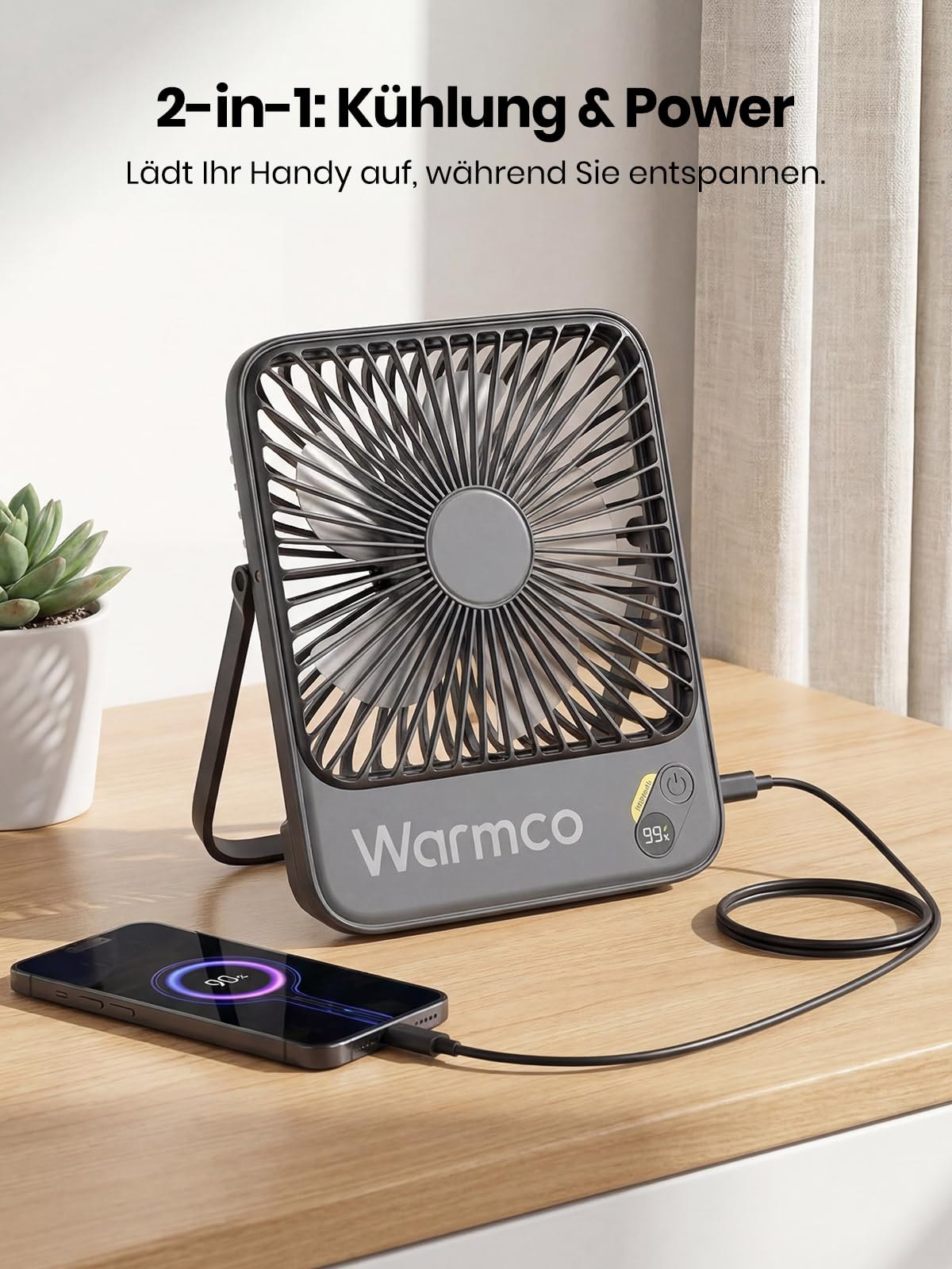 Un ventilatore da tavolo grigio Warmco ricarica uno smartphone.
