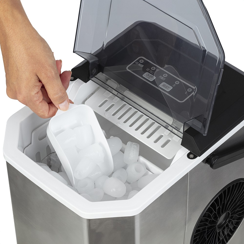 Eine Hand schöpft Eiswürfel mit einer weißen Schaufel aus einer geöffneten Eismaschine.