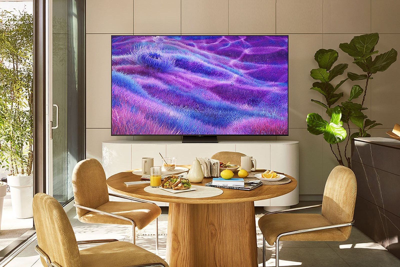 Un tavolo da pranzo con colazione, circondato da sedie gialle, davanti a una grande TV.