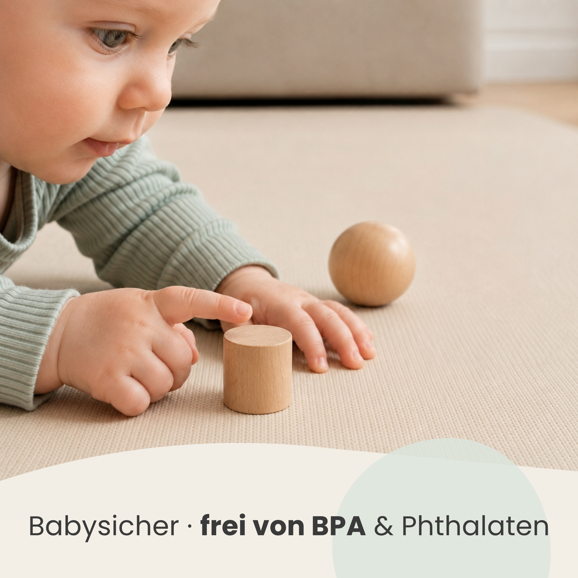 Ein Baby in grüner Kleidung spielt auf einer Matte mit Holzspielzeug.
