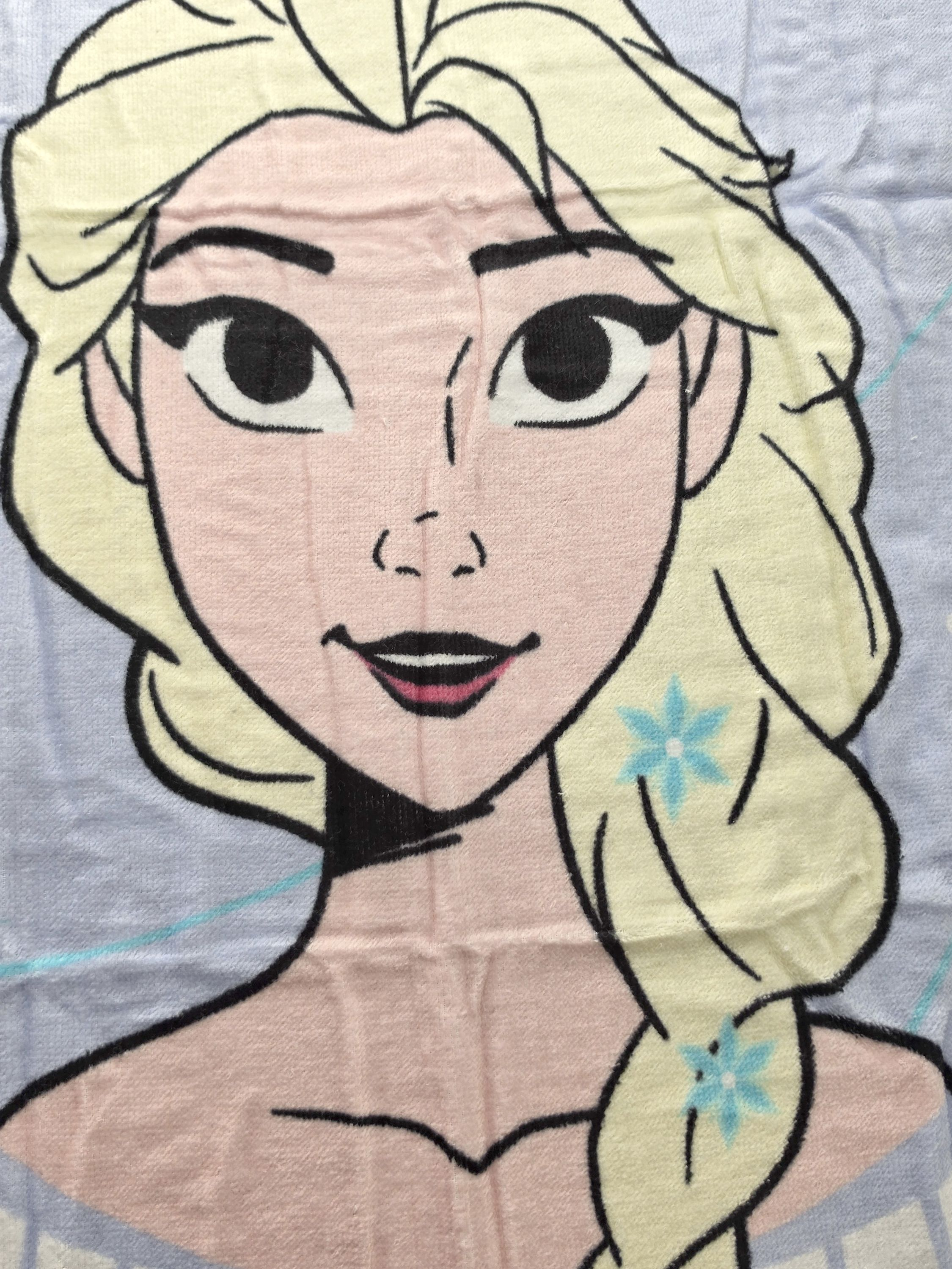 Nahaufnahme von Elsa aus Frozen mit blonden Haaren, blauen Blumen im Zopf und hellblauem Hintergrund.
