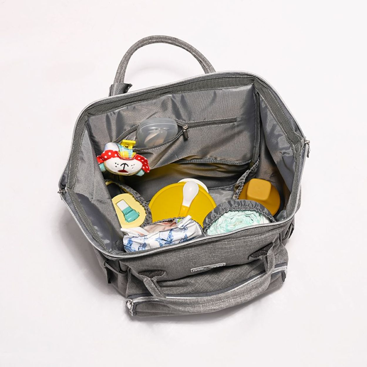 Eine geöffnete graue Wickeltasche mit Babysachen, Spielzeug, Fläschchen und Windeln im Inneren.