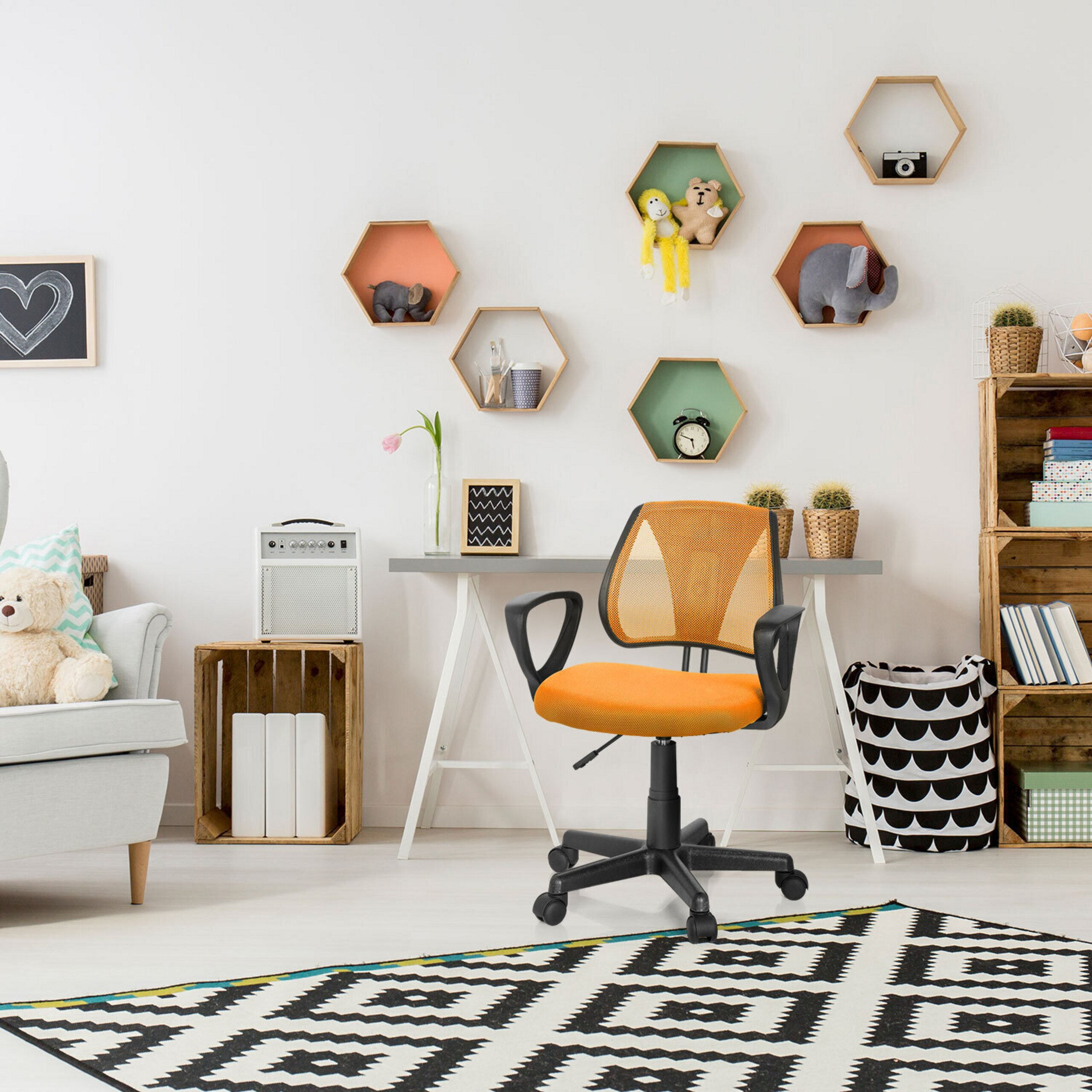 Ein Kinderzimmer mit einem orangen Bürostuhl, einem Tisch, Wandregalen und einem schwarz-weißen Teppich.