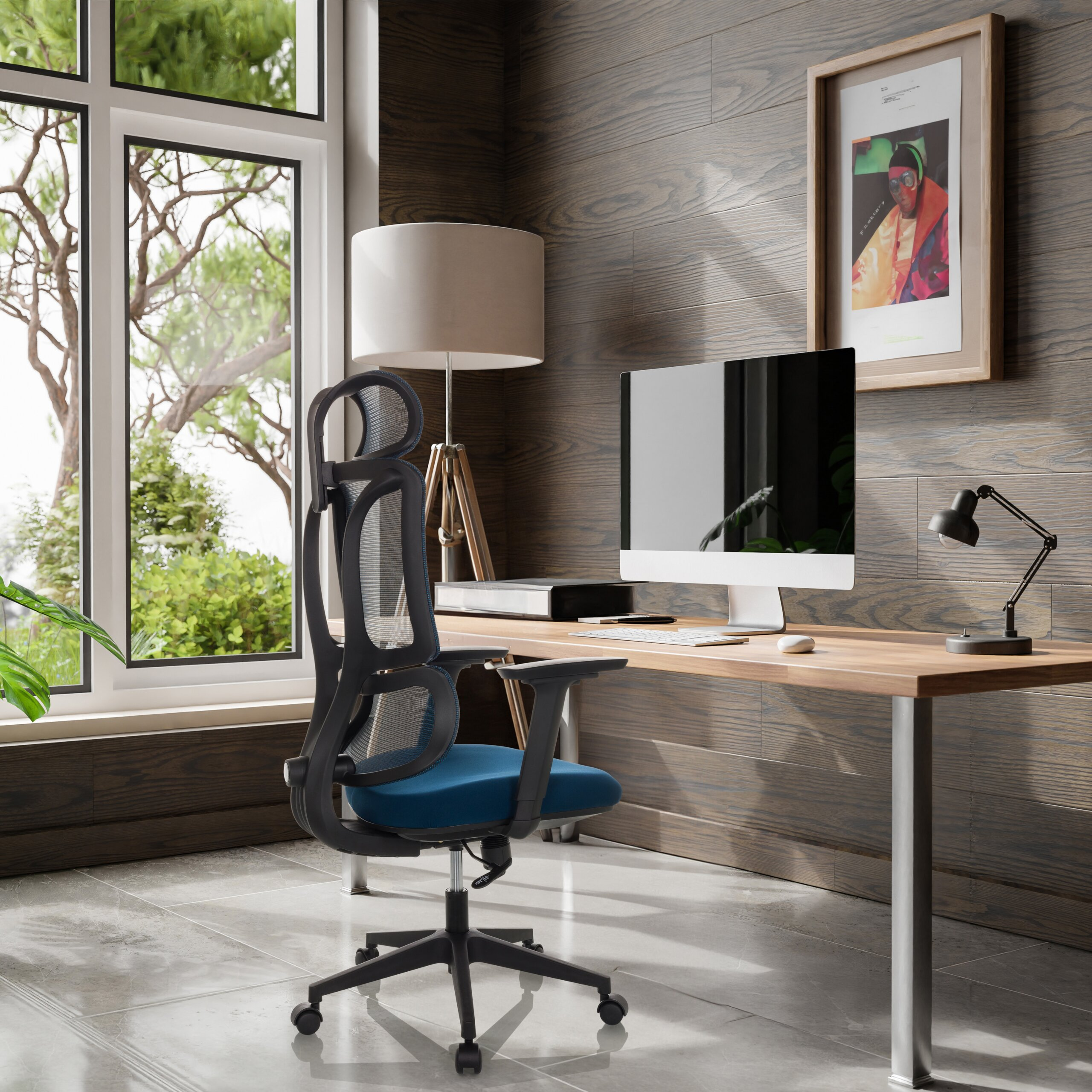 Moderne Arbeitsplatz mit Holzwand, blauem Stuhl, Schreibtisch mit Monitor, Lampe und grossem Fenster mit Aussengruen.