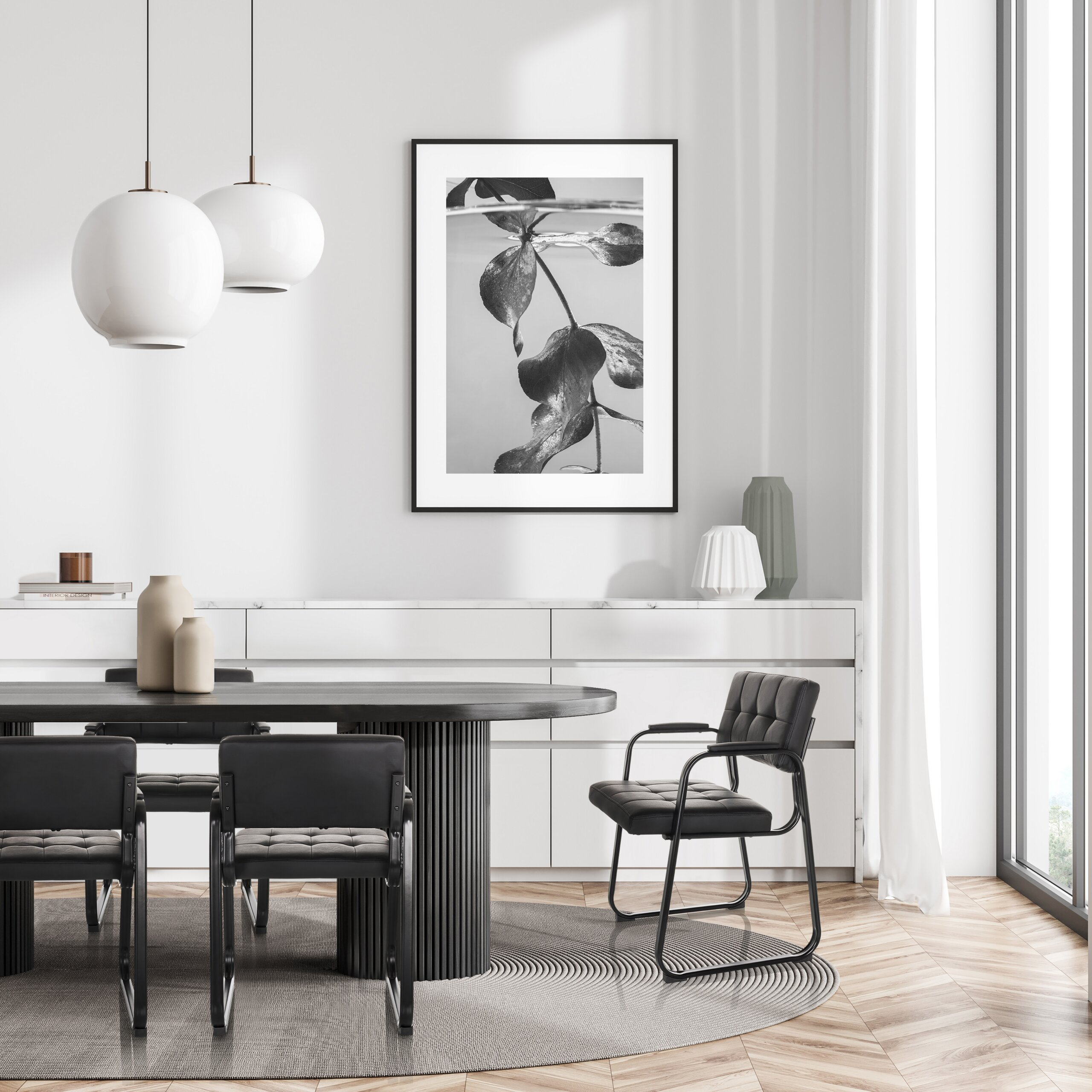 Esszimmer mit dunklem Tisch, schwarzen Stühlen, Hängeleuchten und einem gerahmten Schwarz-Weiß-Bild an der weißen Wand.