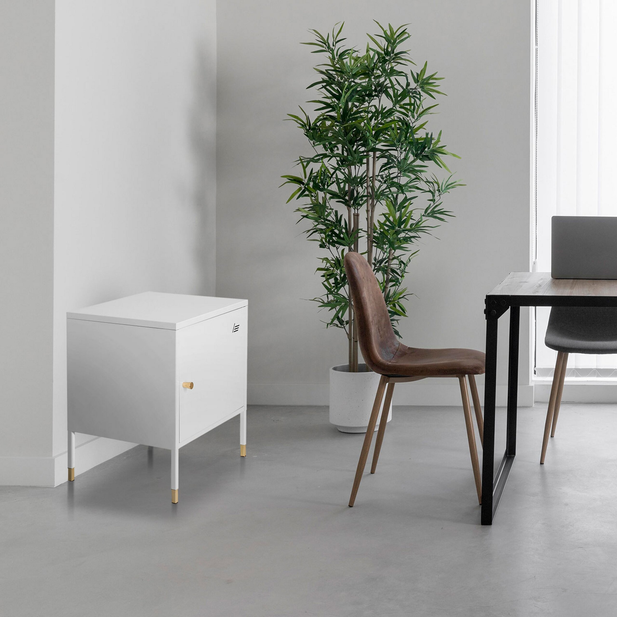 Ein weißer Schrank mit goldenen Füßen steht in einem Raum neben einer Pflanze, einem Holztisch und braunen Stühlen.