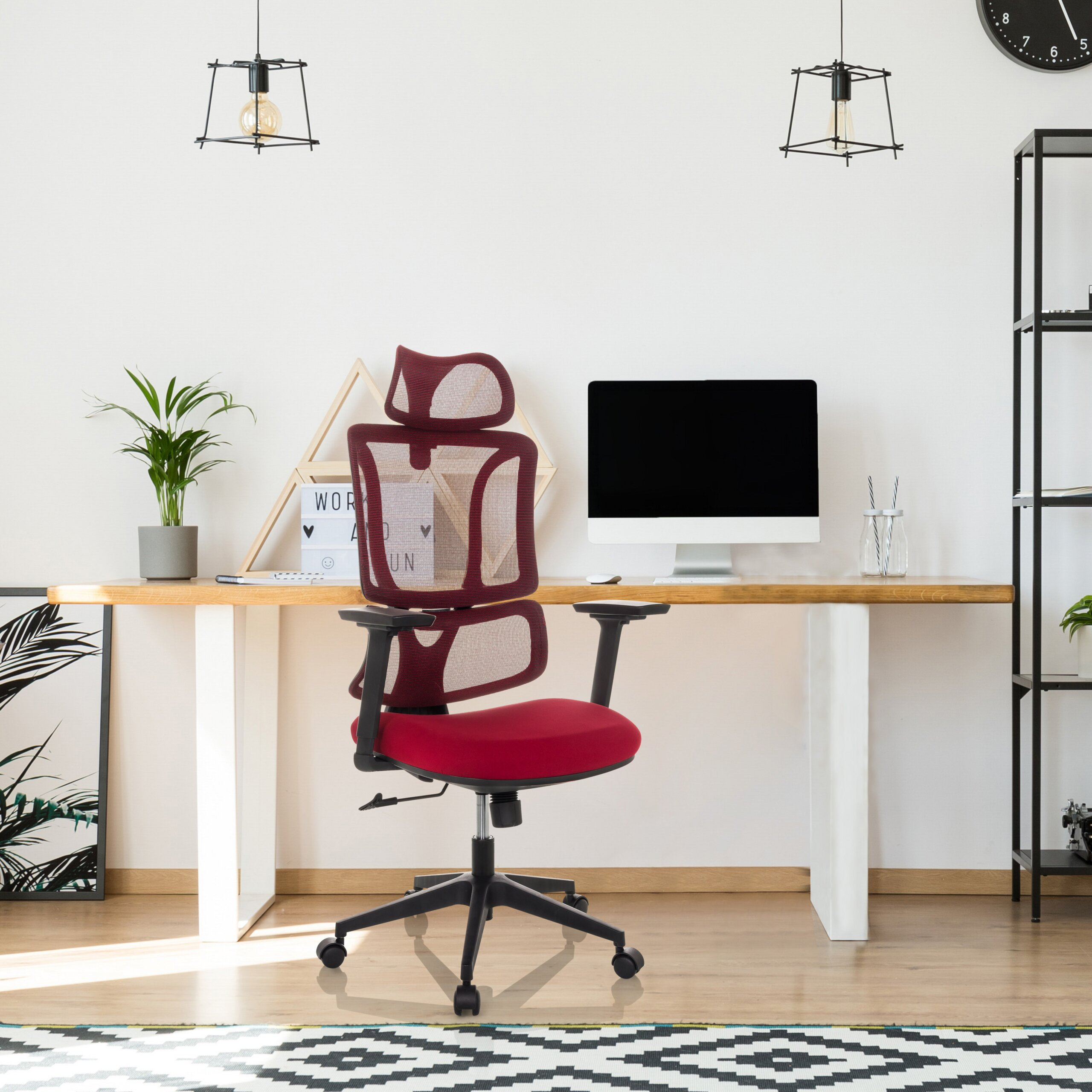 Moderner Arbeitsplatz mit rotem Bürostuhl, Holztisch, Computer und Pflanzen vor weißer Wand.