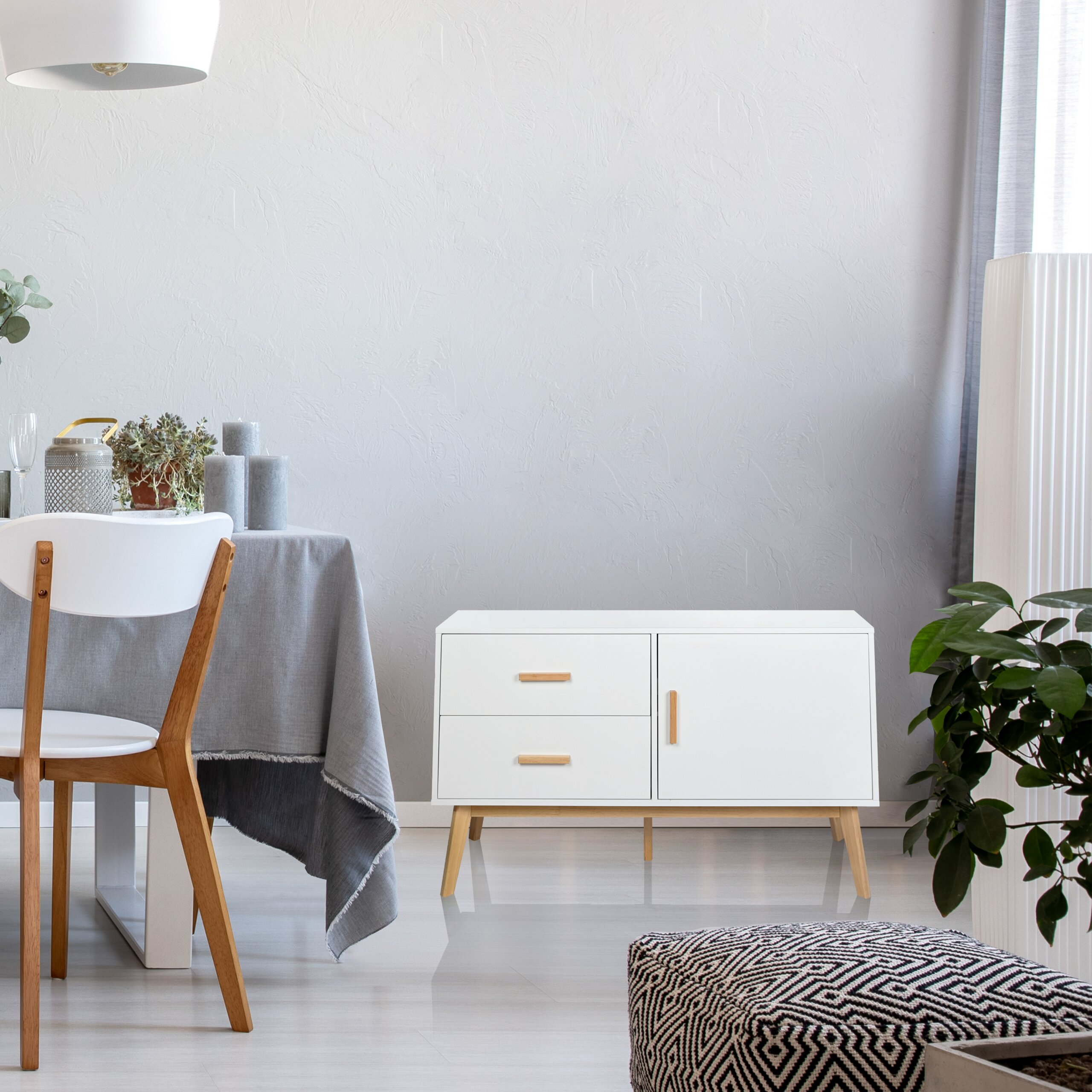Moderne weiße Kommode, Esstisch mit grauer Tischdecke und Pflanzen vor einer grauen Wand.