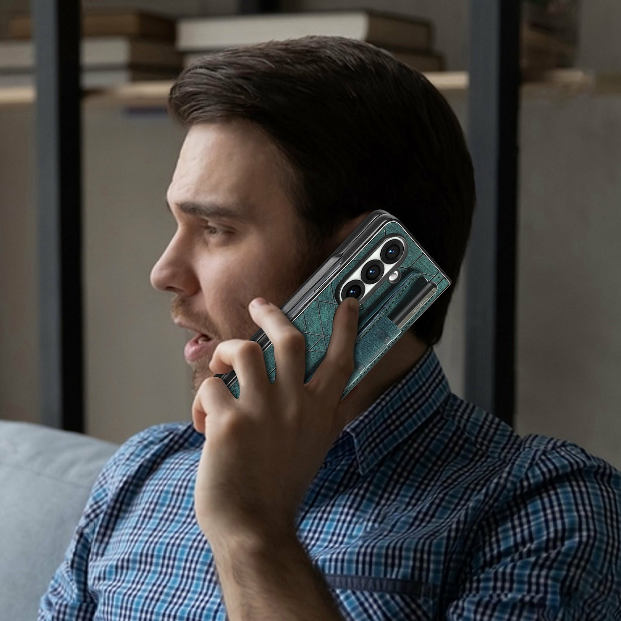 Ein Mann mit blauem Karohemd telefoniert mit einem grünen Smartphone in einer modernen Wohnung.